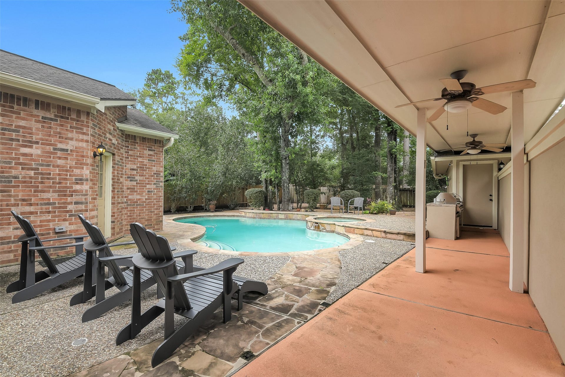 7 Larkspur Trail, The Woodlands, TX 77382 Discover a serene backyard oasis featuring a sparkling pool surrounded by lush greenery. Enjoy outdoor relaxation on the covered patio with ceiling fans and ample seating, perfect for entertaining or unwinding in tranquility.