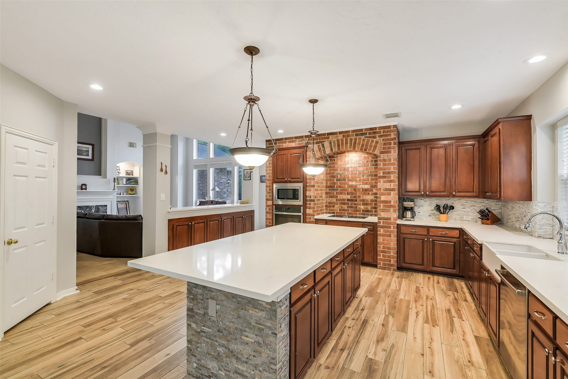 7 Larkspur Trail, The Woodlands, TX 77382 Spacious kitchen with elegant wooden cabinetry, a large central island, and stylish brick accents, perfect for entertaining.