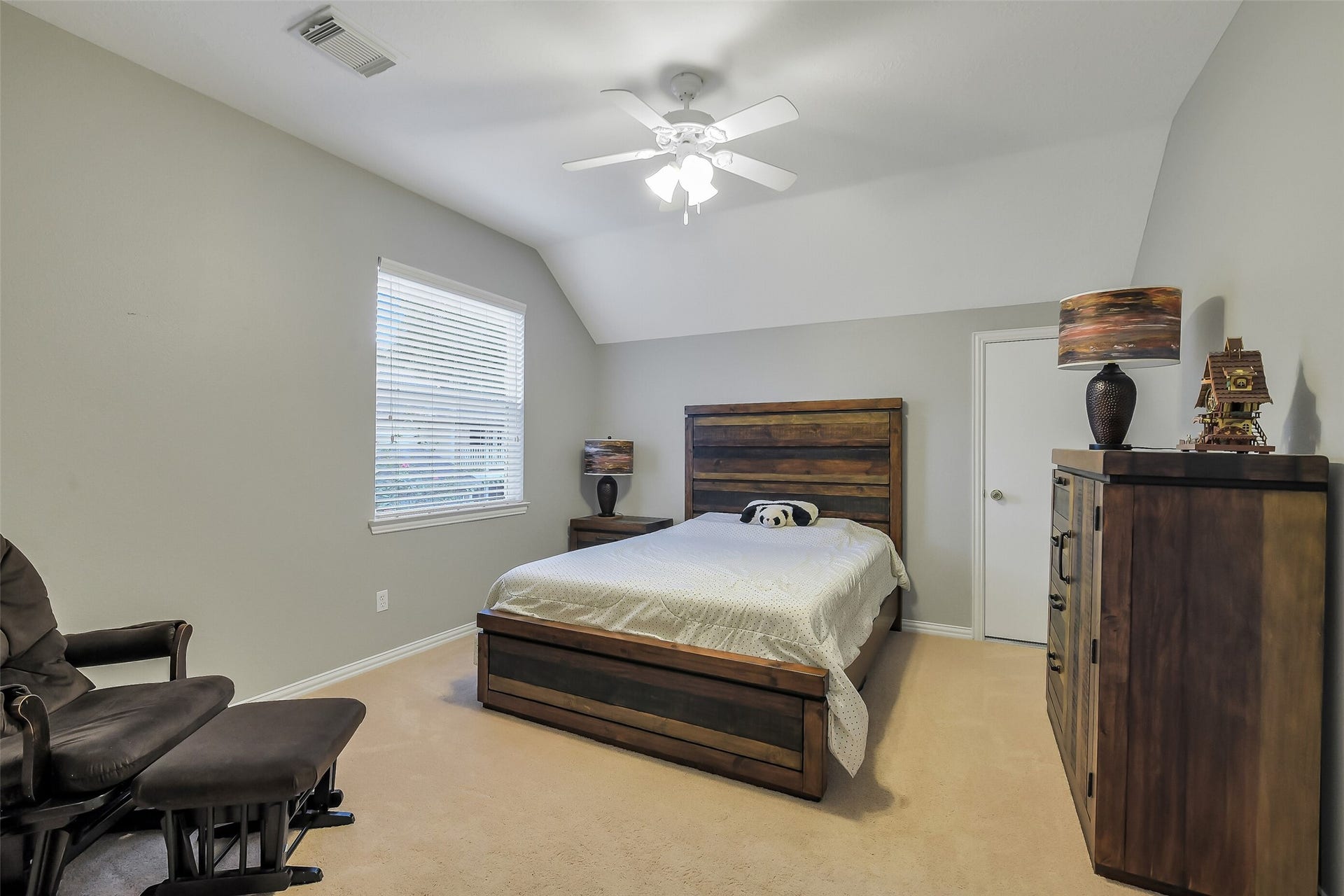 7 Larkspur Trail, The Woodlands, TX 77382 Spacious Guest bedroom featuring a cozy bed with rustic wood furniture, neutral walls, and a ceiling fan for added comfort.
