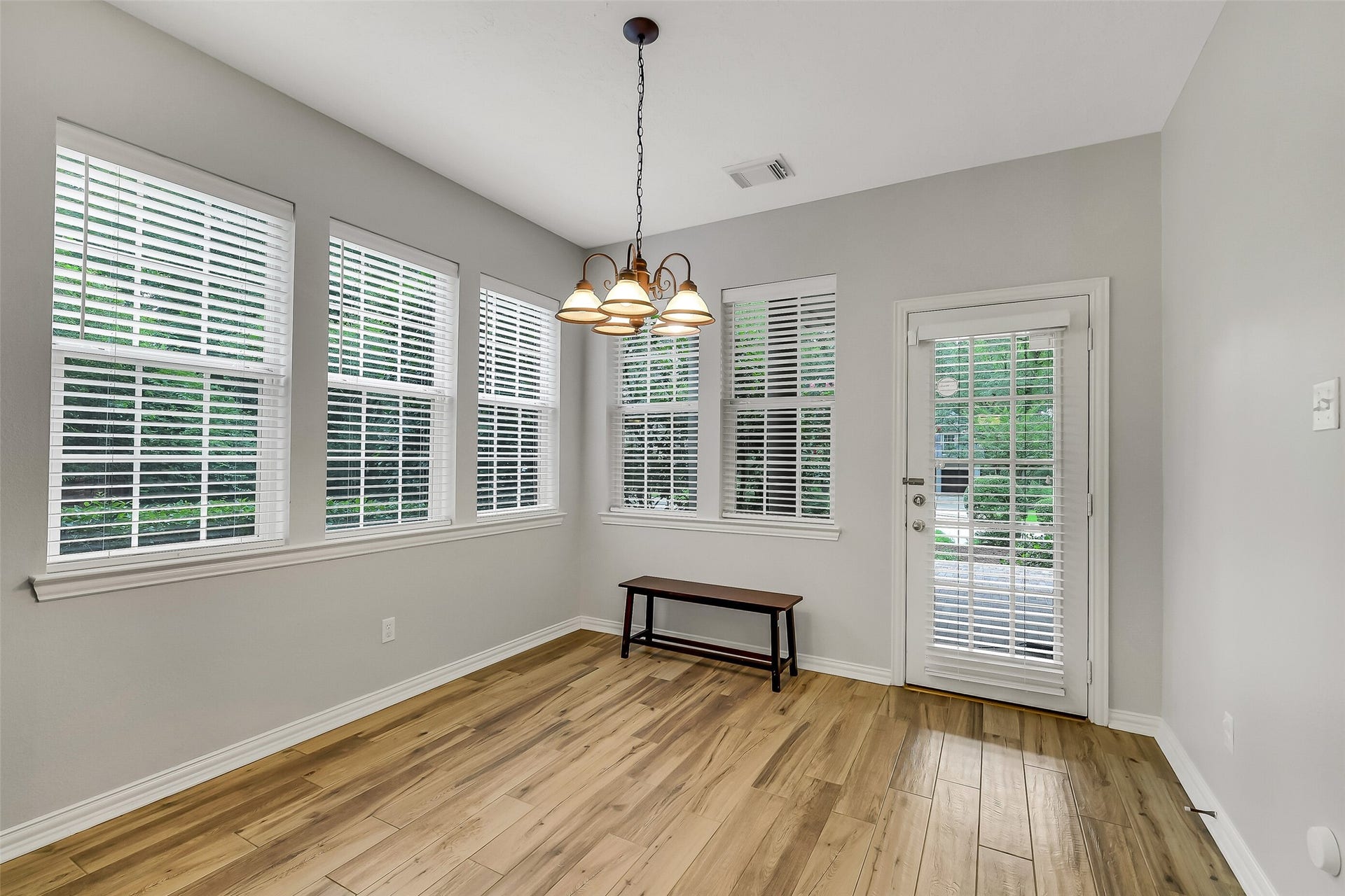 7 Larkspur Trail, The Woodlands, TX 77382 Bright breakfast area with large windows, elegant light fixture, and beautiful hardwood floors, offering a perfect space for gatherings.