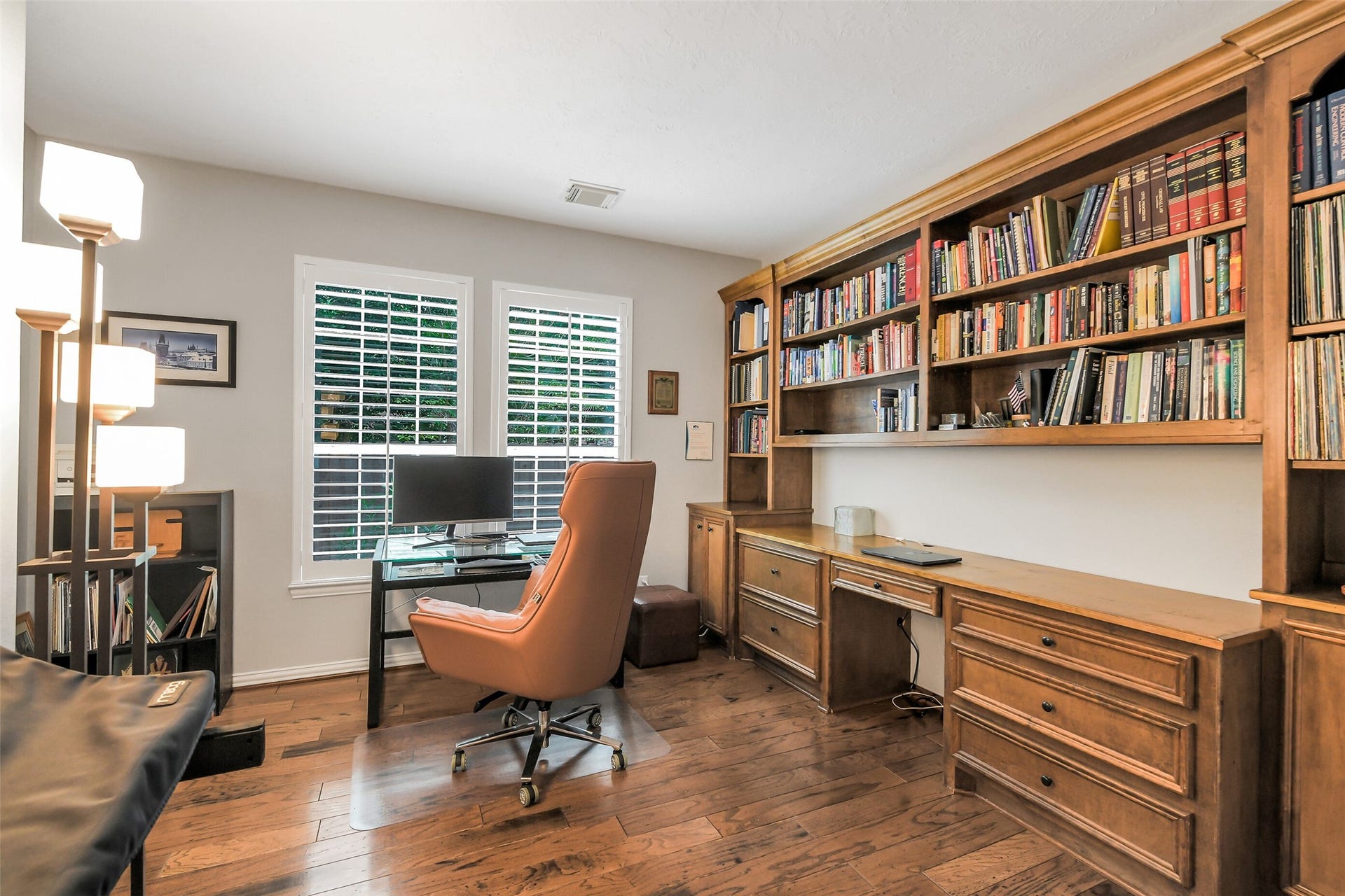 7 Larkspur Trail, The Woodlands, TX 77382 Elegant home office with rich wood flooring, built-in bookshelves, and ample natural light from large windows, offering a perfect space for work and study.