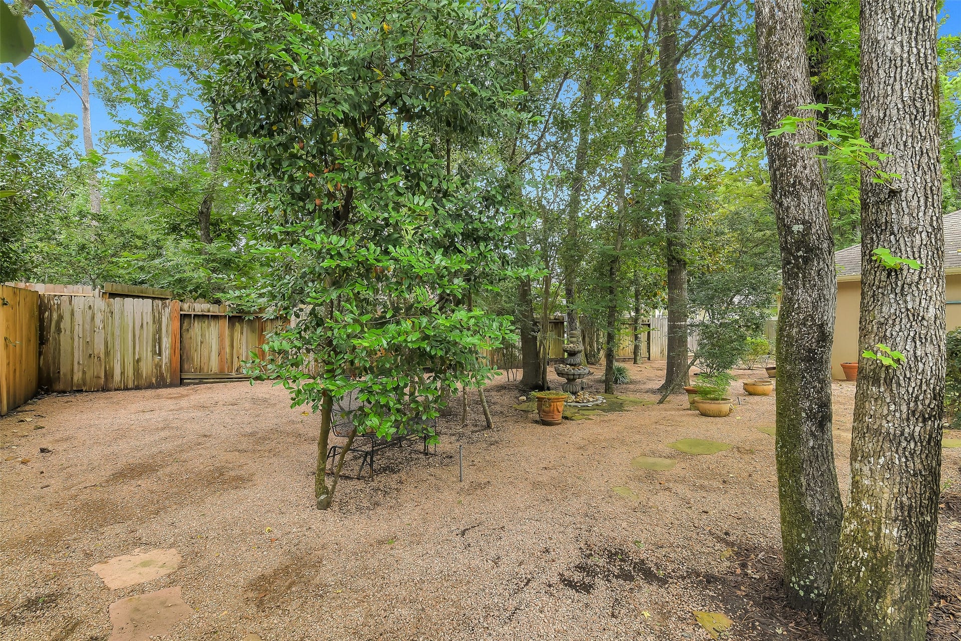 7 Larkspur Trail, The Woodlands, TX 77382 Tranquil backyard oasis featuring a blend of mature trees and gravel pathways, perfect for peaceful outdoor relaxation and gardening.