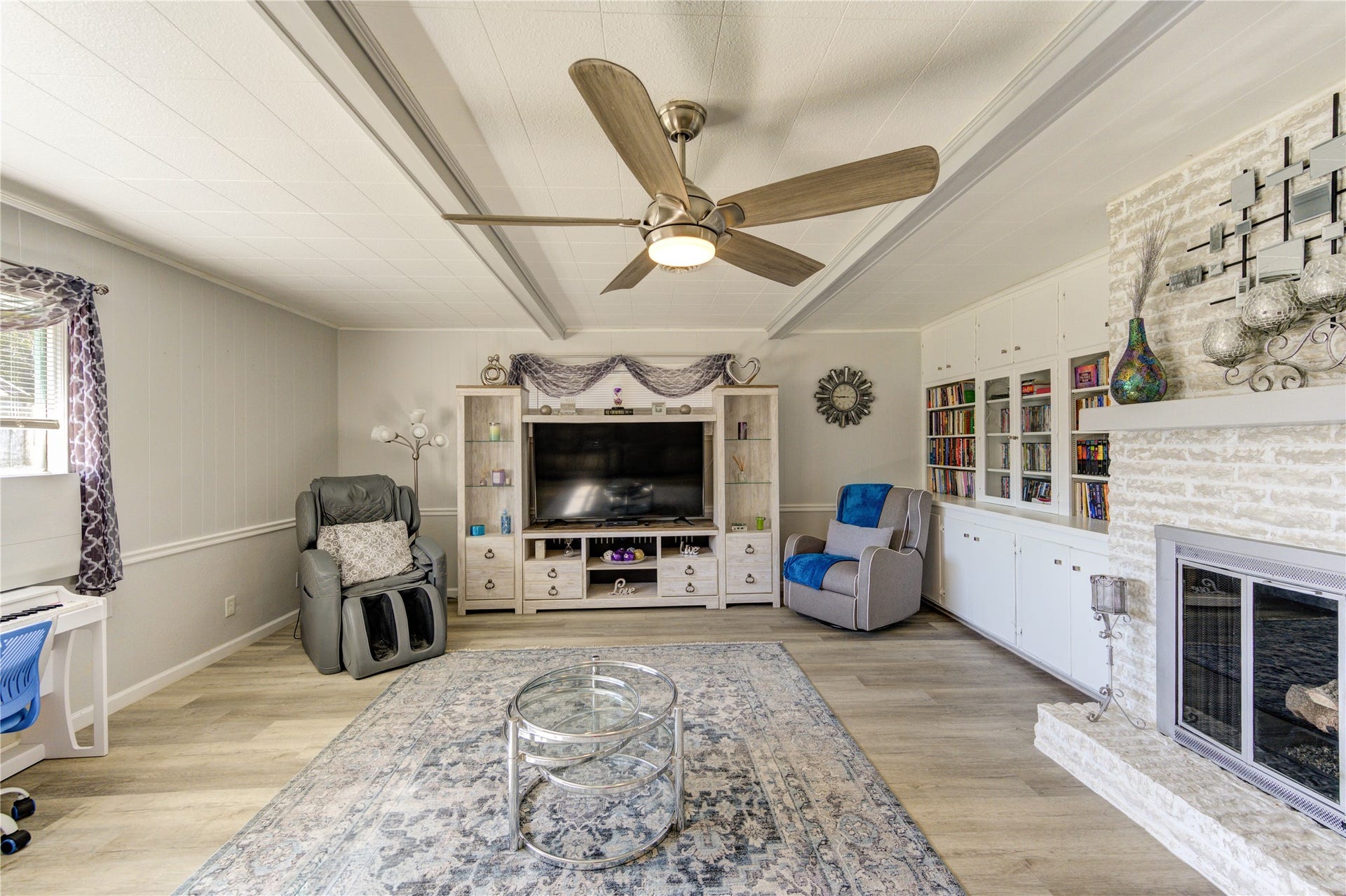 9305 Gettysburg Avenue, Texas City, TX 77591 The den features a modern ceiling fan, built-in bookshelves, and a white painted brick fireplace. Great natural light shines through the large windows.