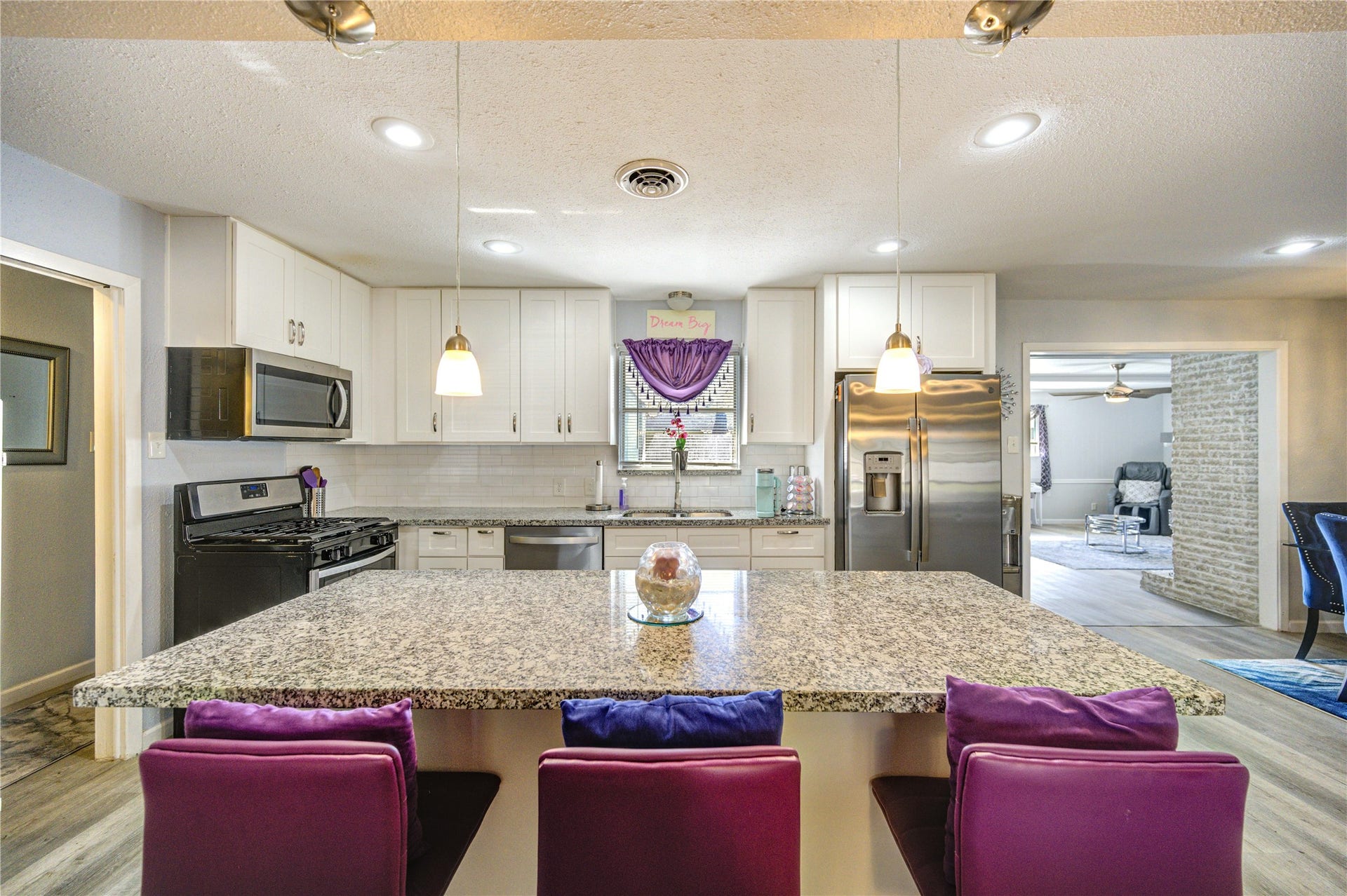 9305 Gettysburg Avenue, Texas City, TX 77591 This modern kitchen features granite countertops, a large island with bar seating, stainless steel appliances, and white cabinetry. It opens into a spacious living area, creating a seamless flow for entertaining.