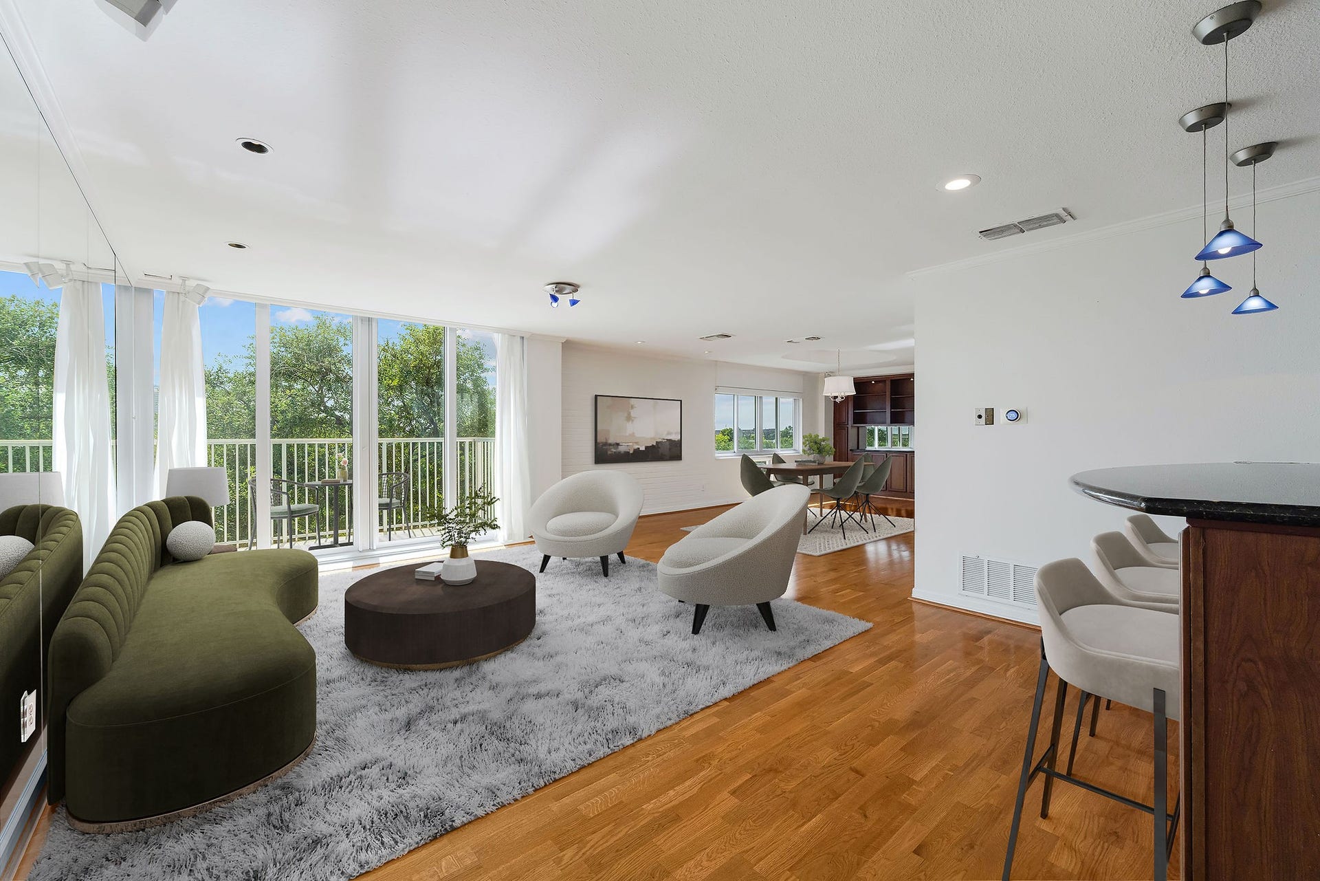 3600 Montrose Boulevard, #501, Houston, TX 77006 This virtually staged photo shows off a spacious open-concept living area with large windows offering abundant natural light and scenic views, featuring sleek wood flooring, modern furnishings, and stylish lighting.