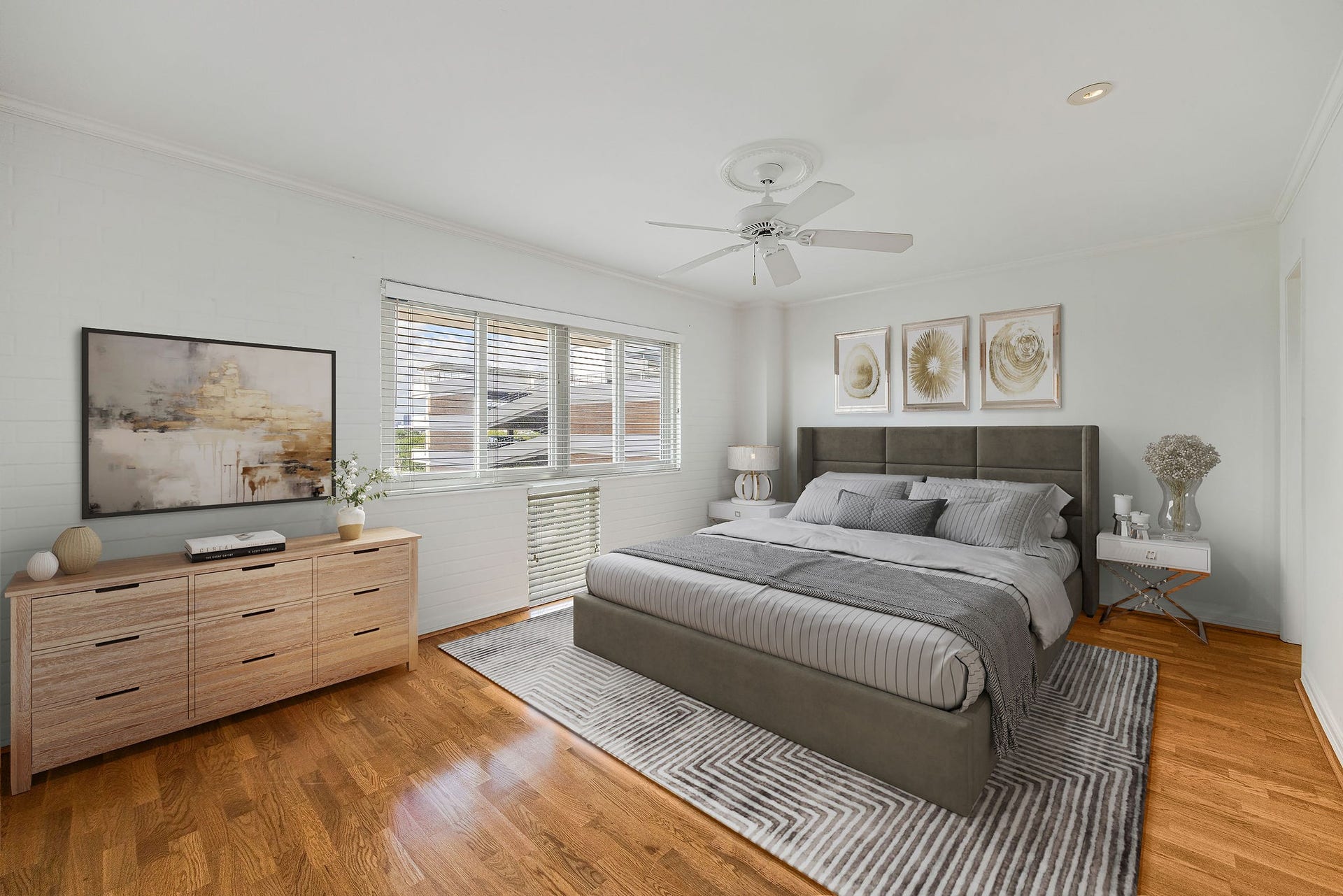 3600 Montrose Boulevard, #501, Houston, TX 77006 This virtually staged photo shows a spacious and bright bedroom featuring hardwood floors, a stylish bed, and elegant decor, complemented by ample natural light from large windows.