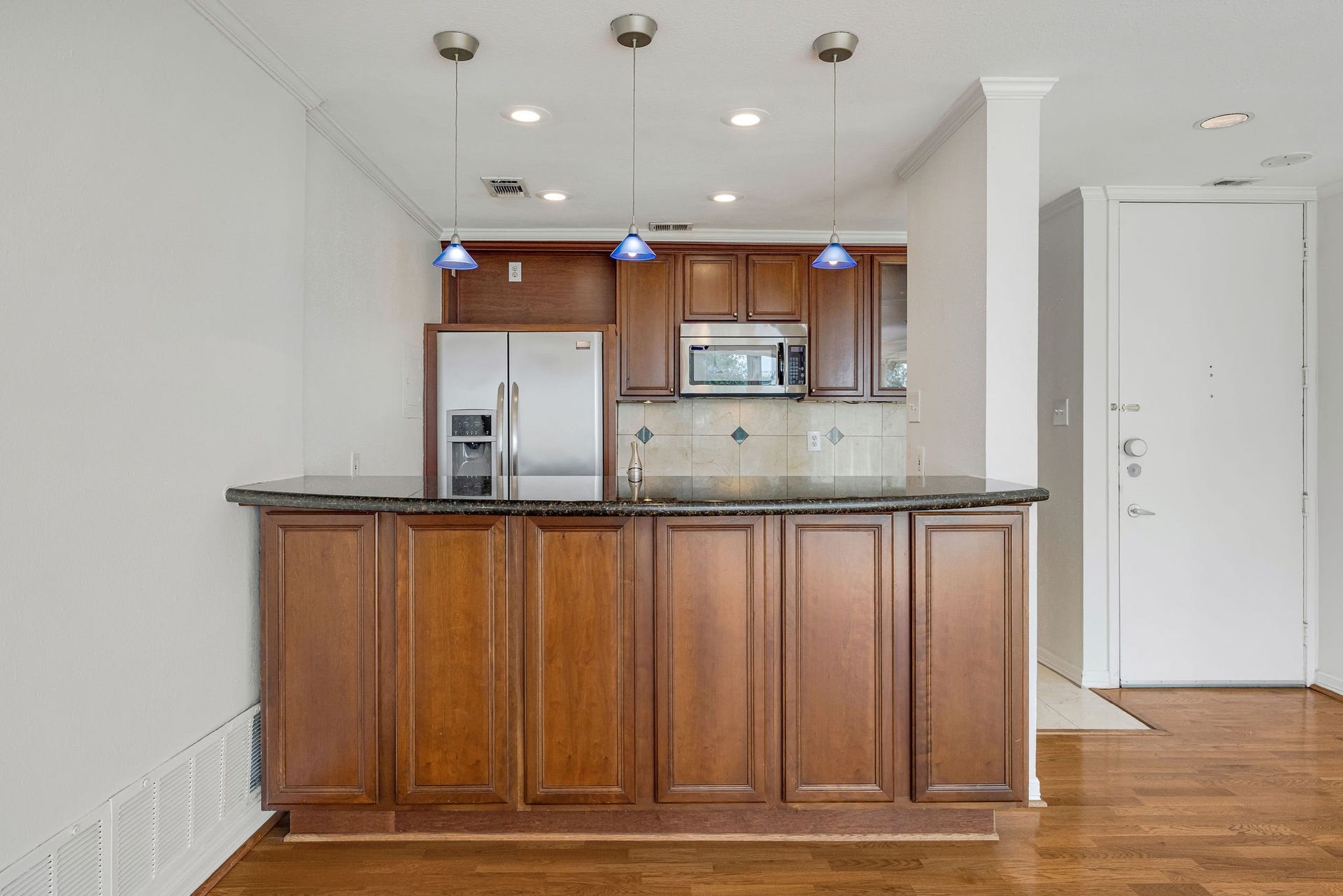 3600 Montrose Boulevard, #501, Houston, TX 77006 Charming kitchen with rich wooden cabinetry, sleek granite countertops, and modern stainless steel appliances, highlighted by elegant pendant lighting.