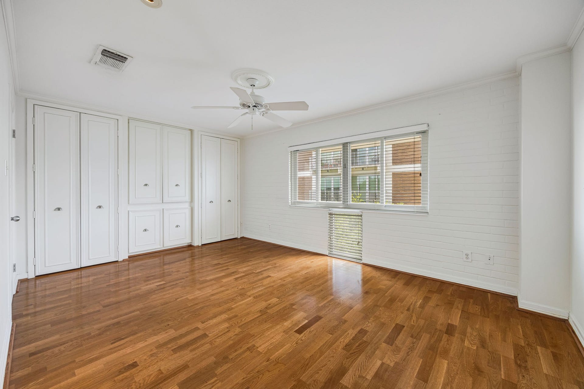3600 Montrose Boulevard, #501, Houston, TX 77006 Spacious bedroom with gleaming hardwood floors, abundant natural light from wide windows, and ample storage with built-in cabinetry.