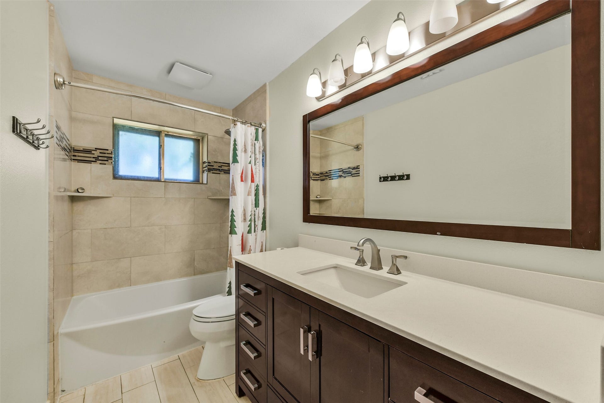 5003 Colombia Drive, Pasadena, TX 77505 Modern bathroom featuring a sleek vanity with ample storage, elegant lighting, and a tiled shower-tub combo with a decorative backsplash.