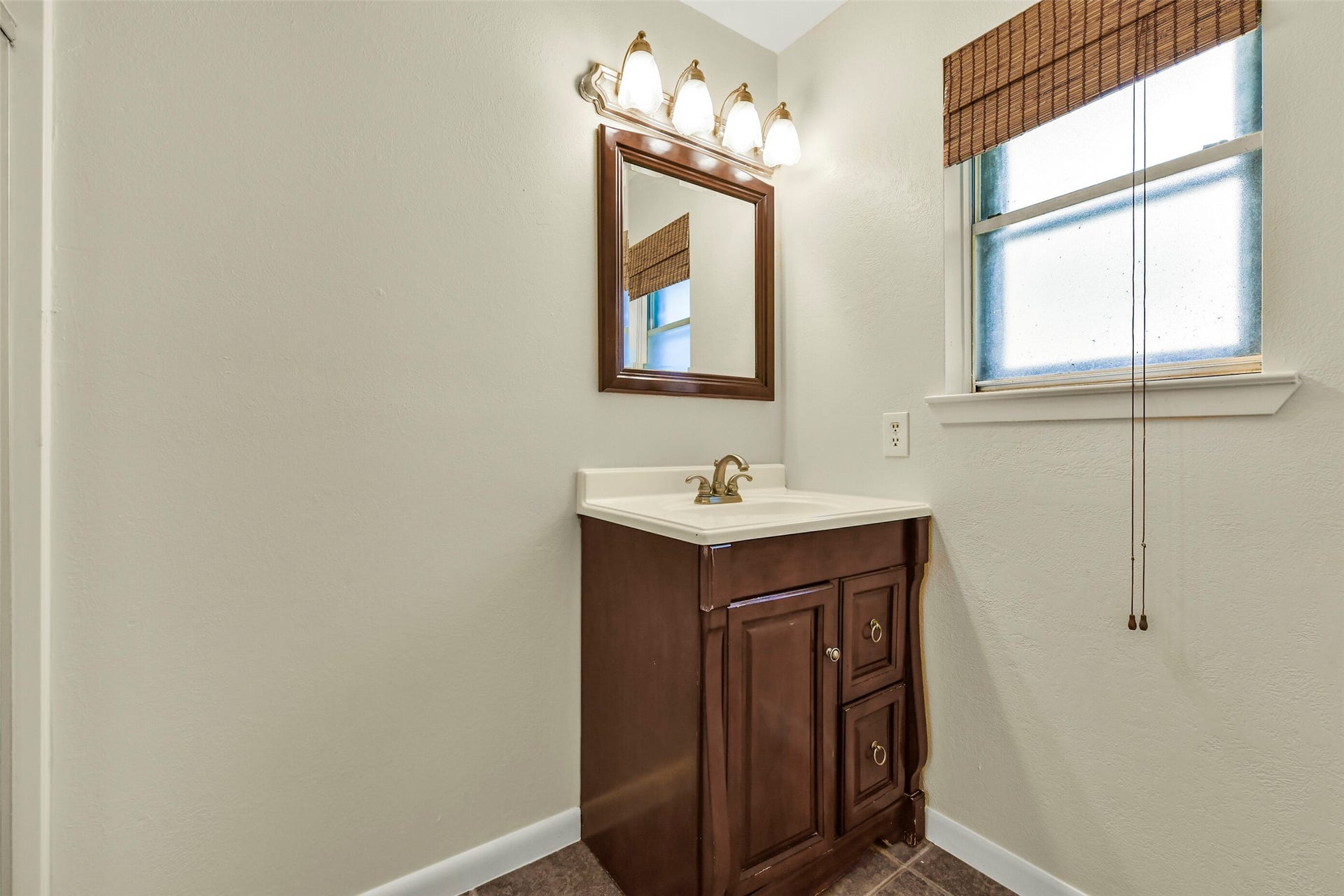 5003 Colombia Drive, Pasadena, TX 77505 Bathroom features a classic dark wood vanity with ample storage, complemented by a sleek mirror and elegant lighting.