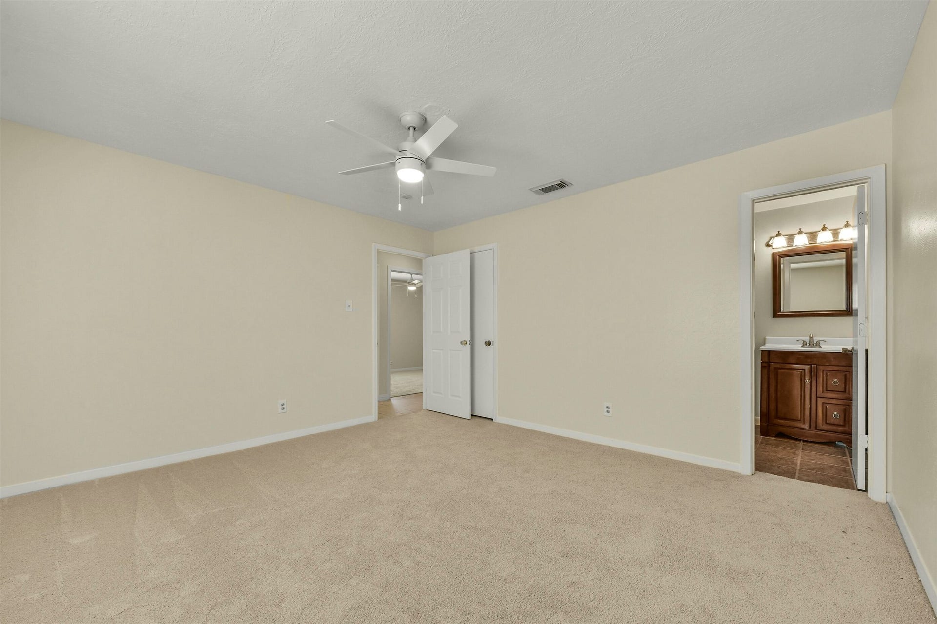 5003 Colombia Drive, Pasadena, TX 77505 Soft carpet, neutral walls, and a ceiling fan, featuring an ensuite bathroom for added convenience.