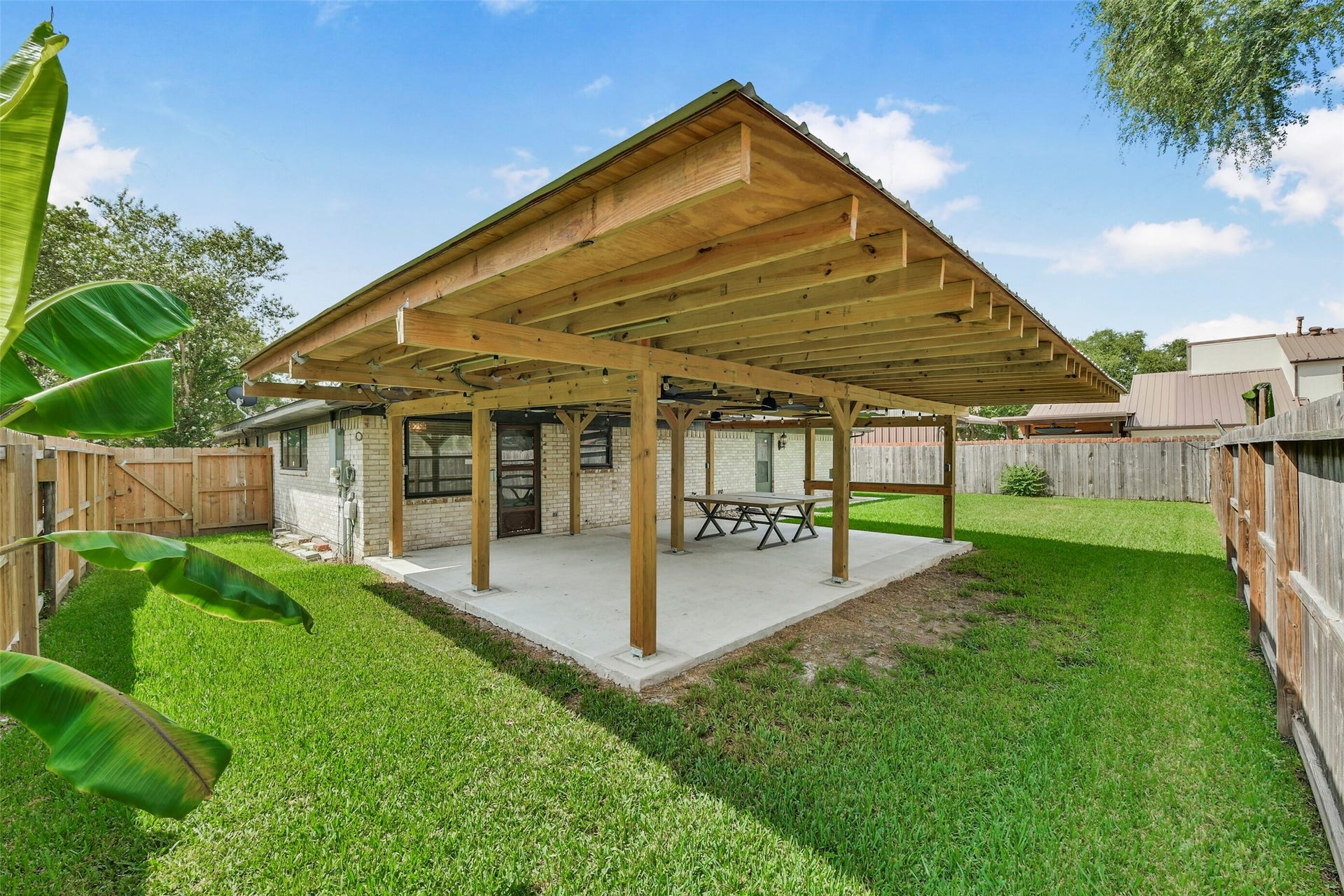 5003 Colombia Drive, Pasadena, TX 77505 Backyard featuring a large wooden pergola, perfect for outdoor gatherings and relaxation, surrounded by a lush green lawn and privacy fencing.
