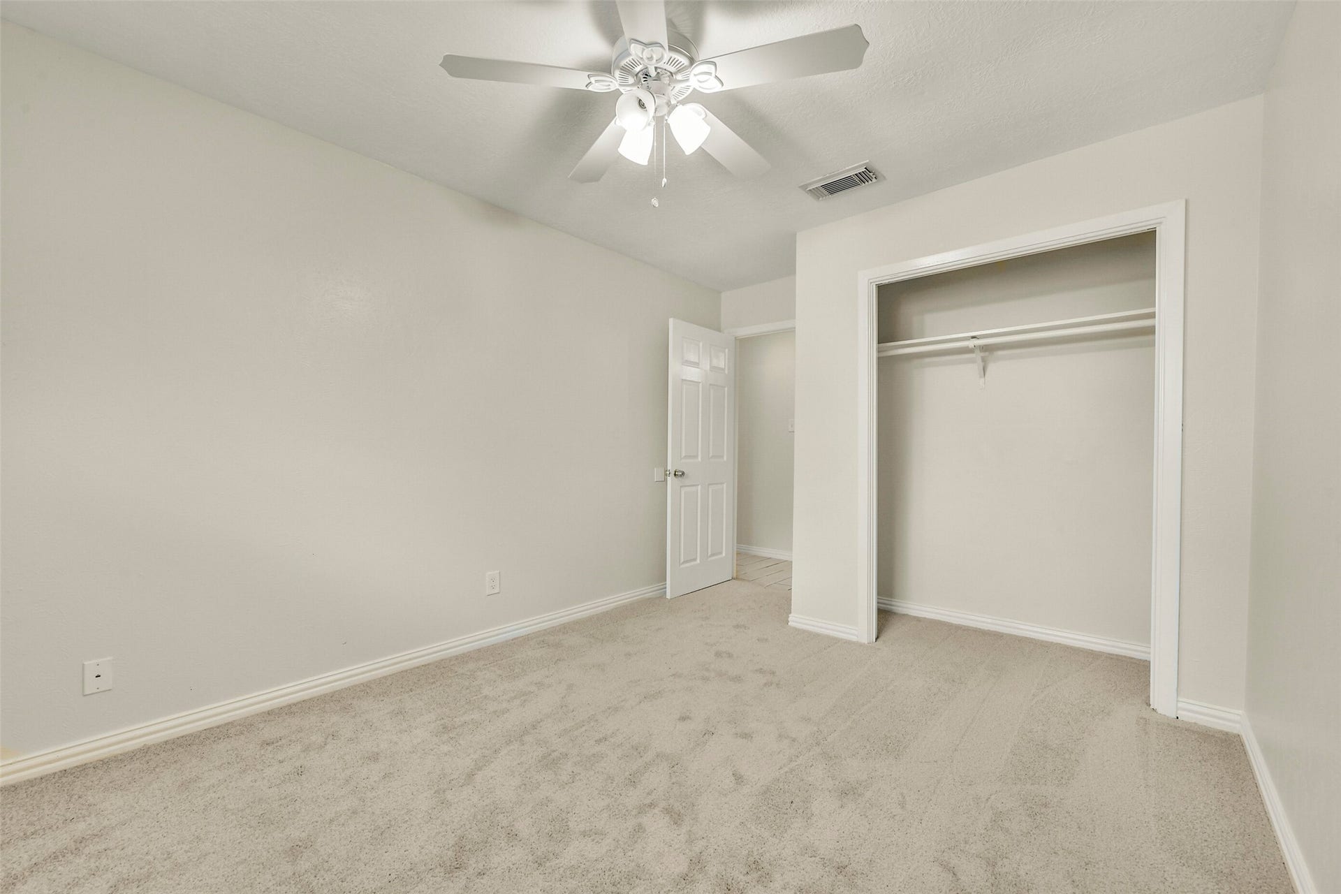 5003 Colombia Drive, Pasadena, TX 77505 Cozy bedroom with plush carpeting, a ceiling fan, and a spacious closet, offering a comfortable and inviting atmosphere.