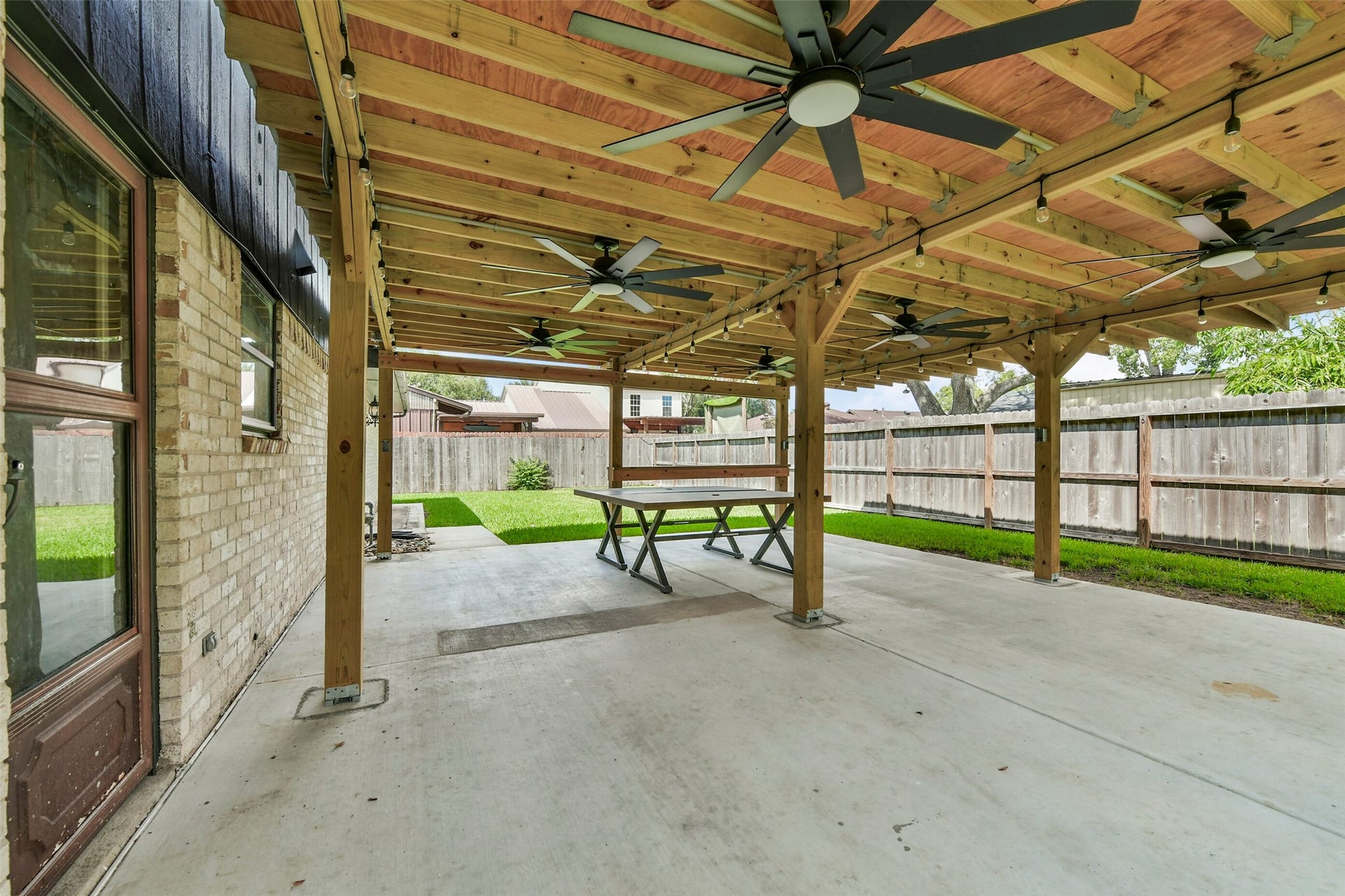 5003 Colombia Drive, Pasadena, TX 77505 Covered patio with multiple ceiling fans, perfect for outdoor entertaining, overlooking a lush, fenced backyard.