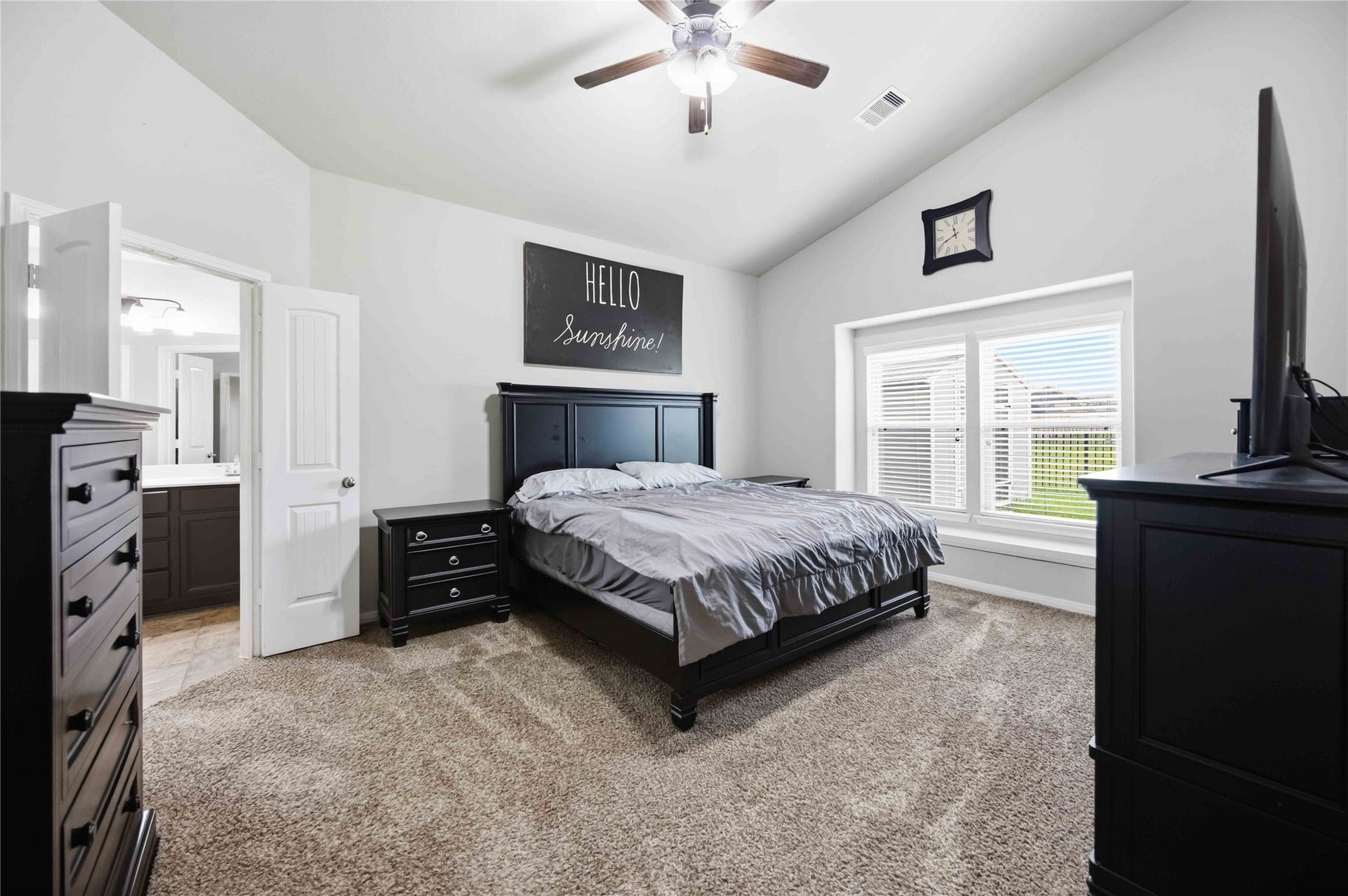 712 Rim Water Drive, Alvin, TX 77511 Primary bedroom with vaulted ceilings, featuring a comfortable bed, elegant dark wood furniture, and large windows that let in plenty of natural light.