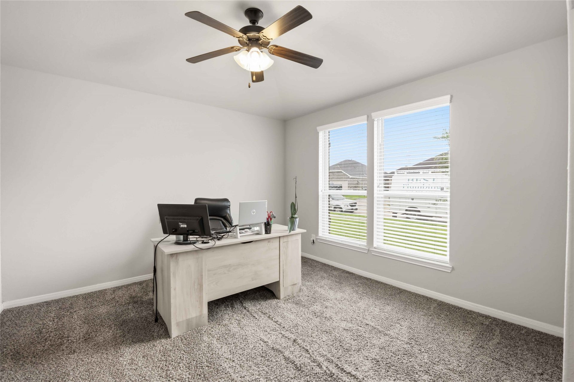 712 Rim Water Drive, Alvin, TX 77511 Bright and inviting home office featuring large windows, plush carpeting, and a ceiling fan for comfort.