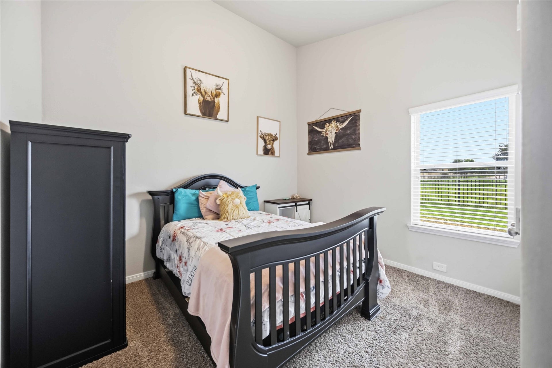 712 Rim Water Drive, Alvin, TX 77511 Cozy bedroom featuring a stylish dark wood bed, soft carpeting, and abundant natural light from a large window overlooking the backyard.