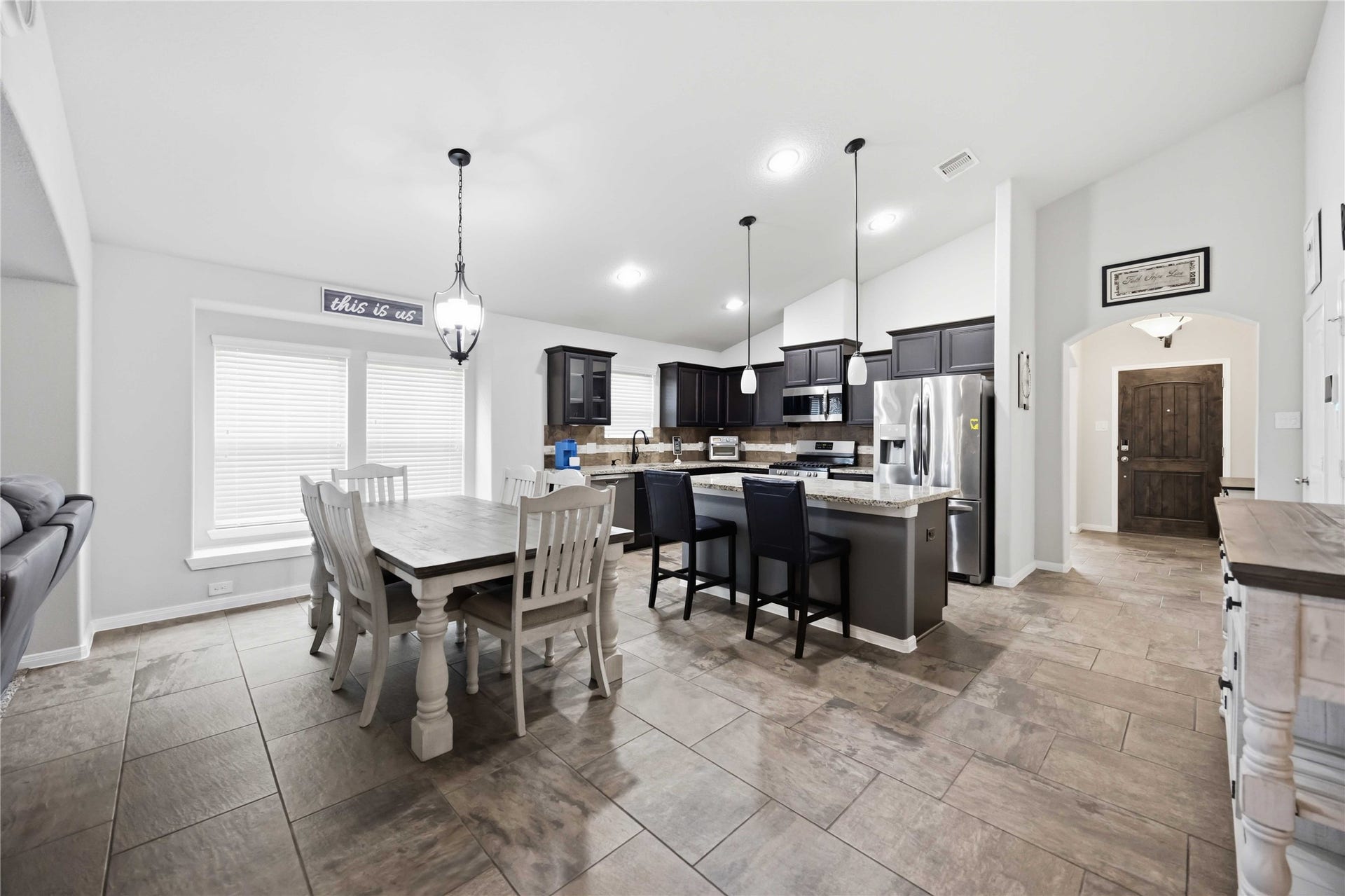 712 Rim Water Drive, Alvin, TX 77511 Spacious open-concept kitchen and dining area featuring modern appliances, elegant dark cabinetry, and a large island with bar seating, perfect for entertaining.