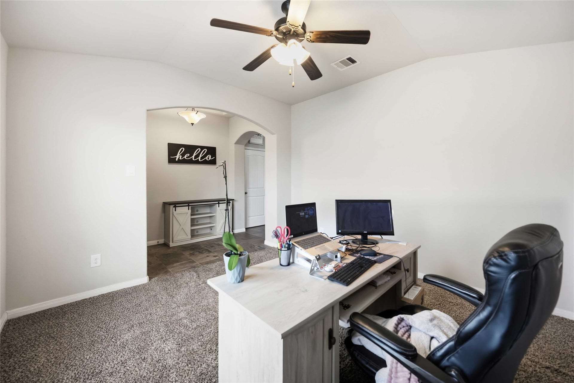 712 Rim Water Drive, Alvin, TX 77511 Spacious home office with plush carpeting, a ceiling fan, and a welcoming archway leading to a separate area, ideal for productivity and comfort.