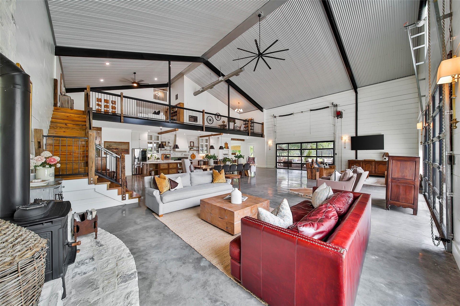 Entertainer's dream featuring an expansive open-concept living, dining and kitchen area with dramatic 8'x16' and 10'x16' remote-controlled vertical lift glass bay doors, creating a seamless transition between indoor luxury and outdoor living.