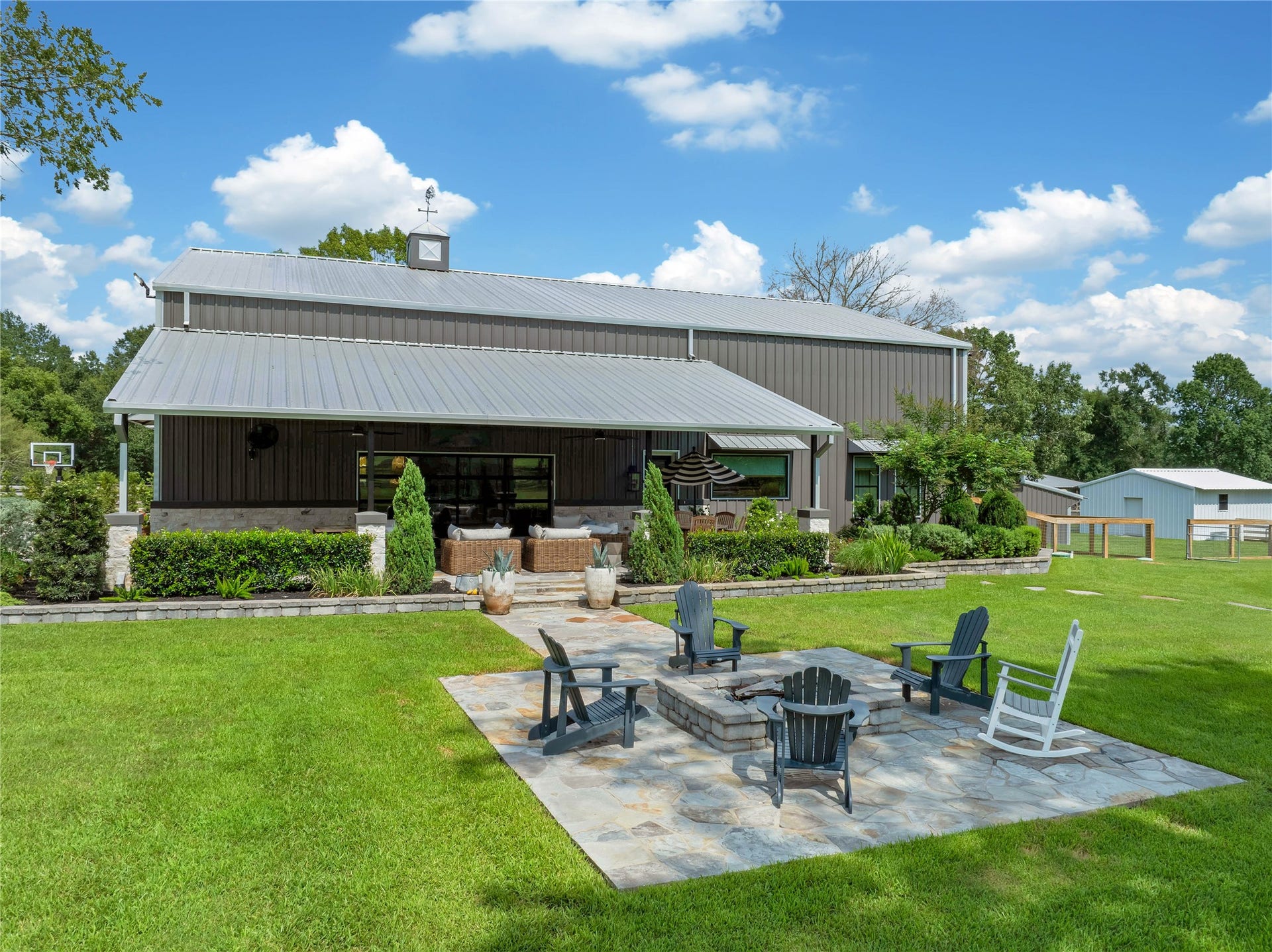 Private side yard oasis featuring an oversized covered patio, custom stone fire pit, professional landscaping and expansive green space perfect for entertaining.