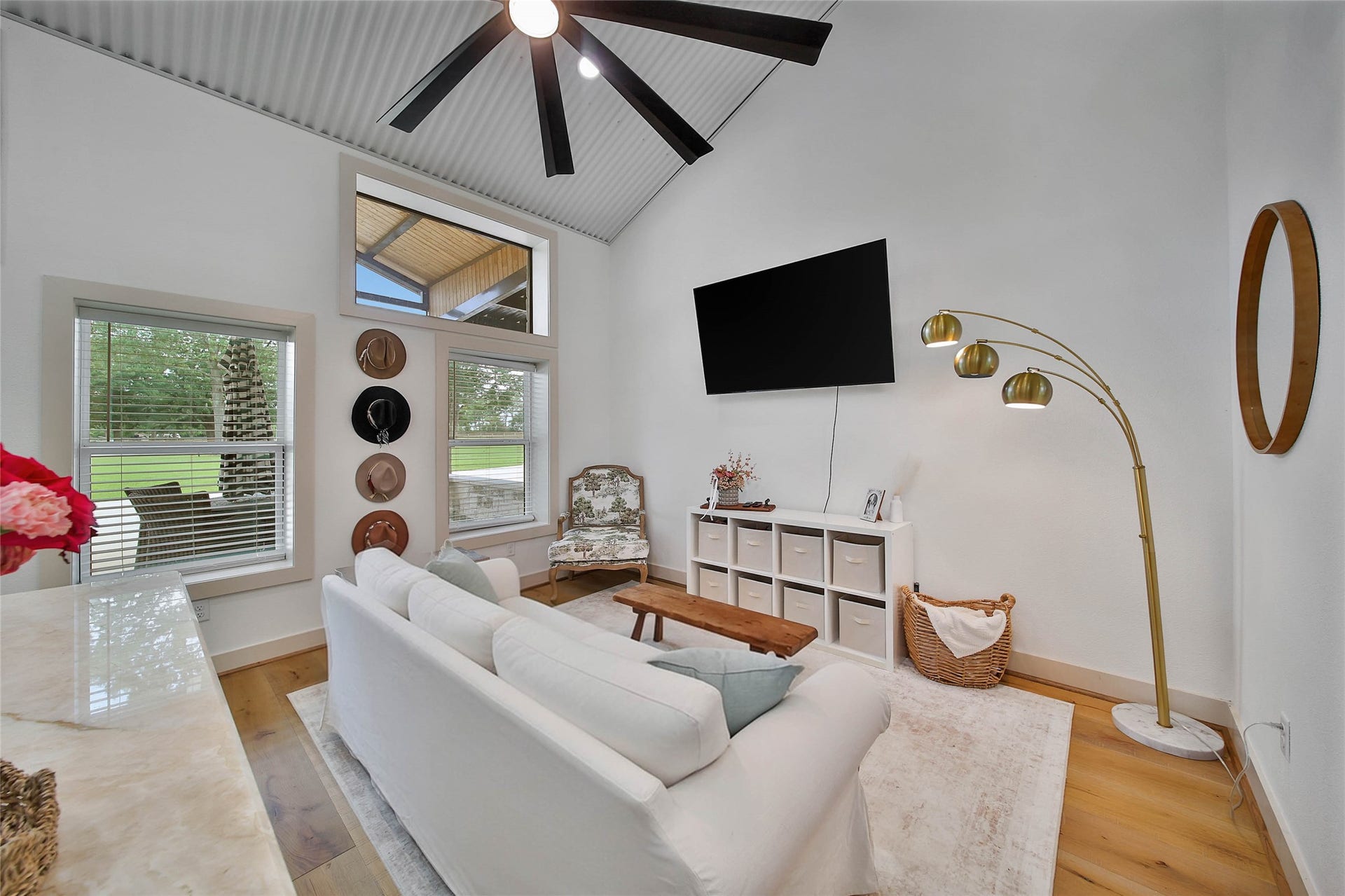 Bright garage apartment living room features soaring metal ceilings, hardwood floors, abundant natural light and an open-concept layout overlooking the covered patio.