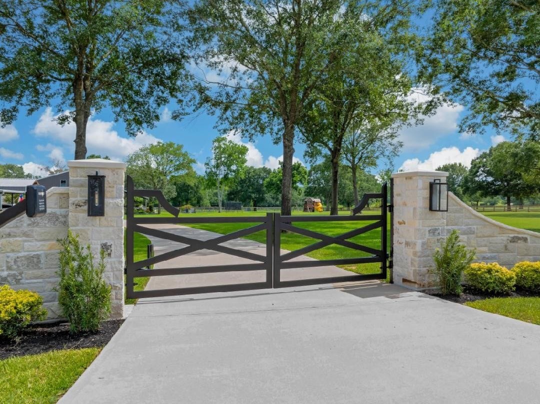 Custom double gated entrance with stone monuments, stone culverts, dual automatic LiftMaster gate motors, keypad access, exit sensors, and a sweeping extra wide driveway welcoming you to this exceptional 5.93-acre estate.
