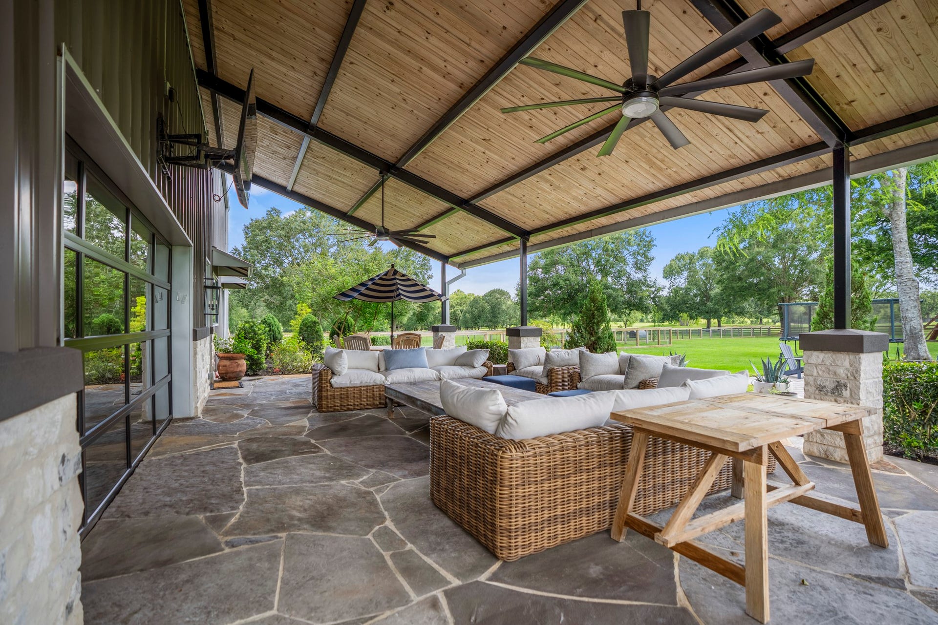 Exceptional outdoor living with an oversized covered patio featuring tongue-and-groove wood ceiling, exposed steel beams, oversized fans and 45x20 flagstone flooring.