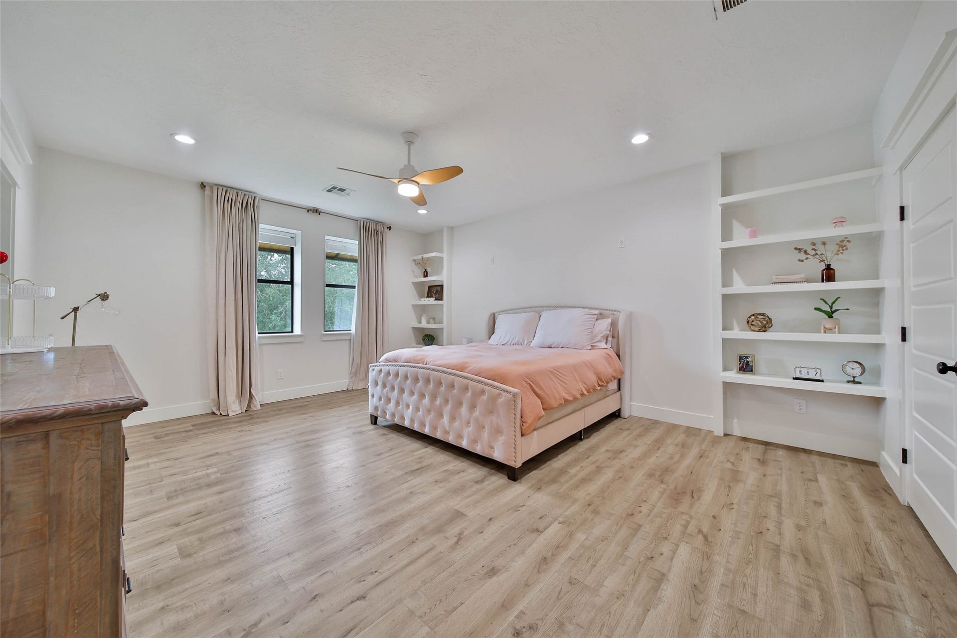 Spacious upstairs secondary bedroom with recessed lighting, ceiling fan, and built-in shelving.