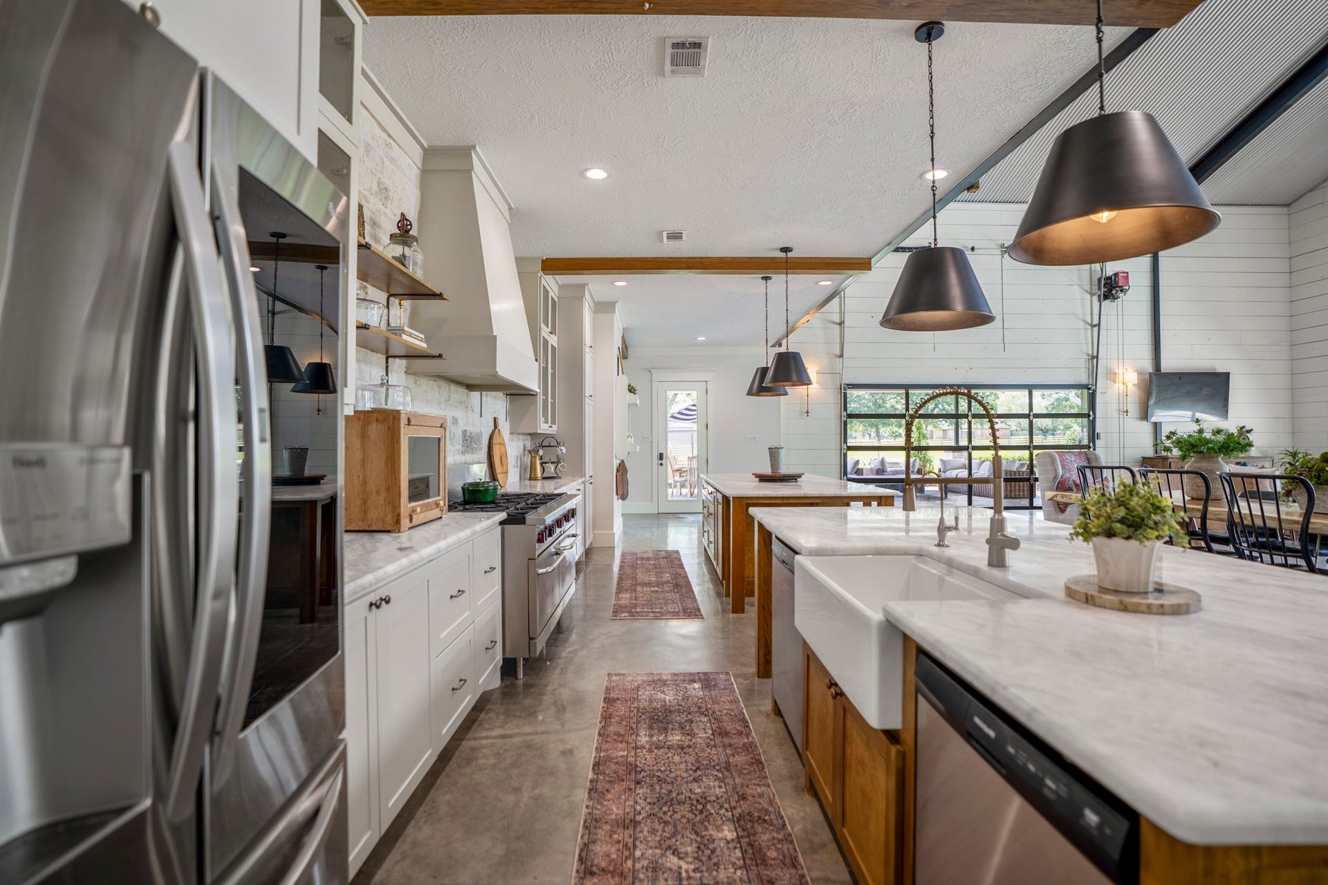 Gourmet kitchen featuring dual oversized islands with farmhouse sink, double dishwashers and designer pendant lighting.