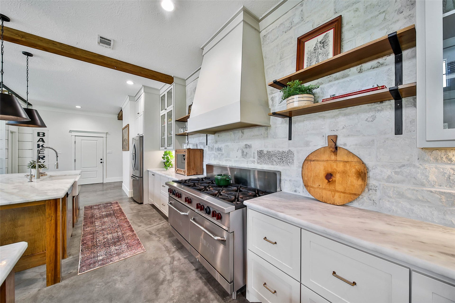 A chef's dream featuring a commercial-grade 10-burner double-oven range with custom vent hood, coffee bar, oversized walk-in pantry, and abundant storageall accented by exposed wood beams and designer finishes.