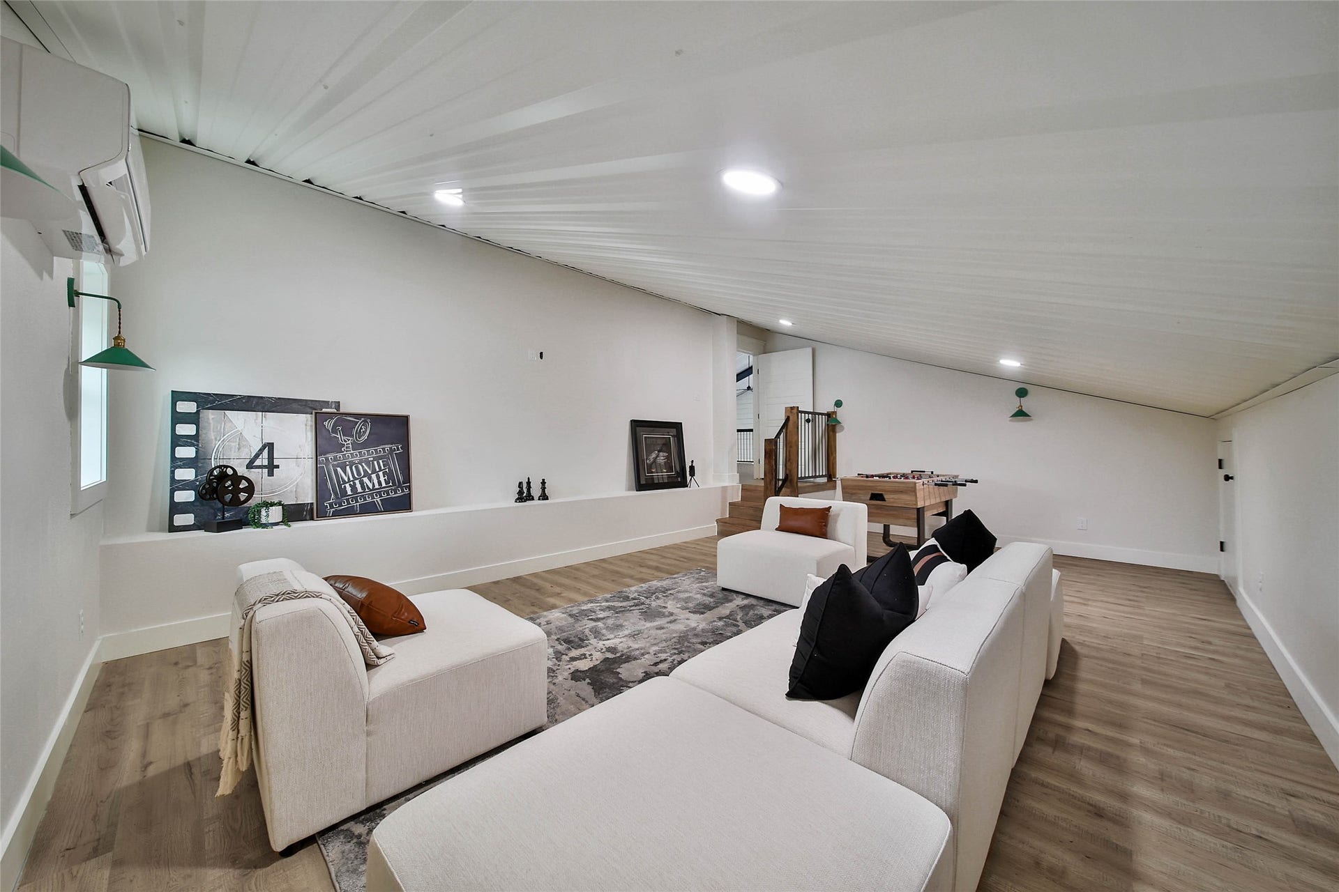 Spacious upstairs media room with mini-split HVAC, corrugated metal ceiling, recessed lighting, and ample space for movie nights, gaming, or a billiards table.