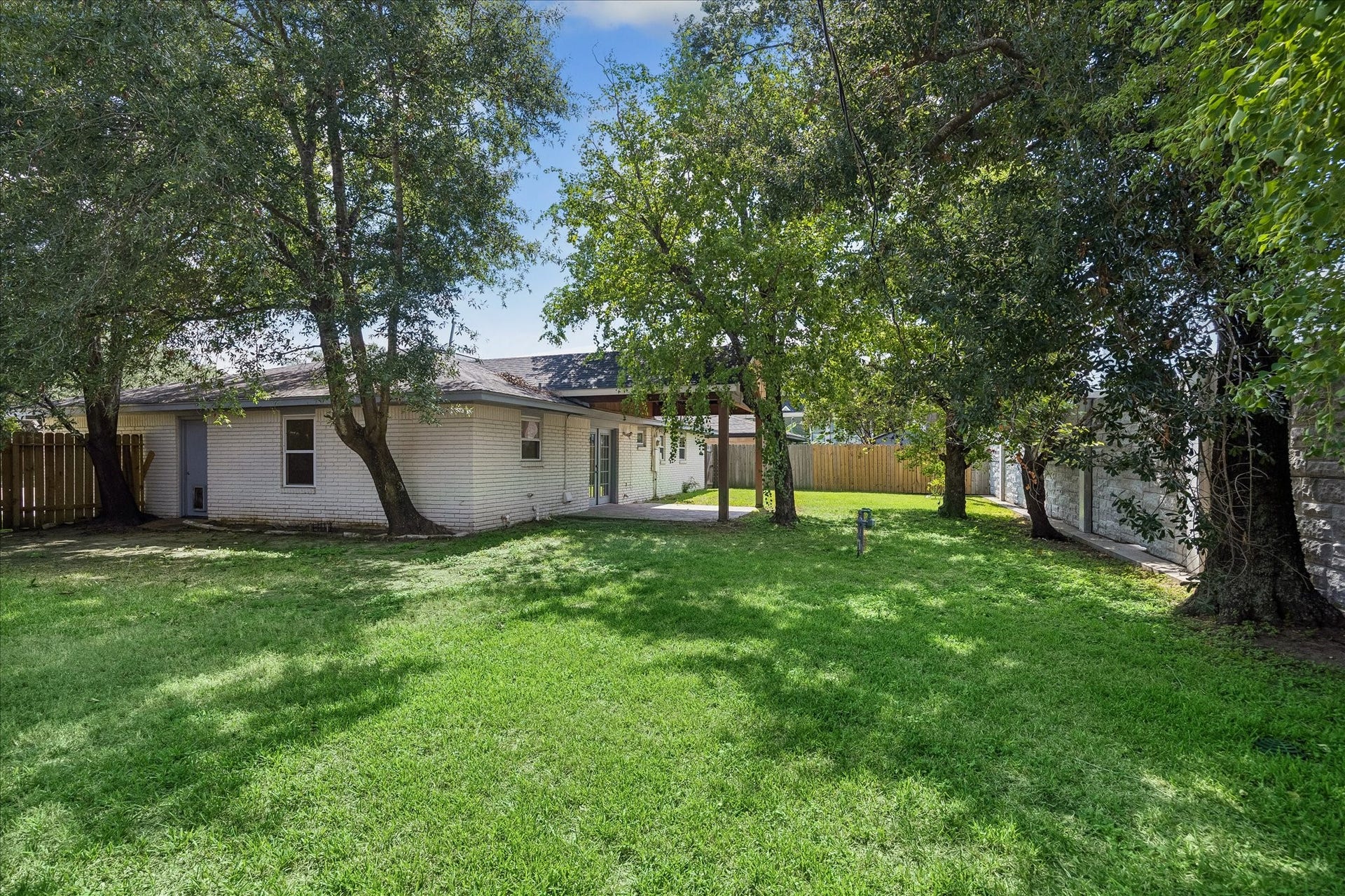 Expansive backyard shaded by mature trees, offering plenty of room for outdoor entertaining, play, or simply relaxing.
