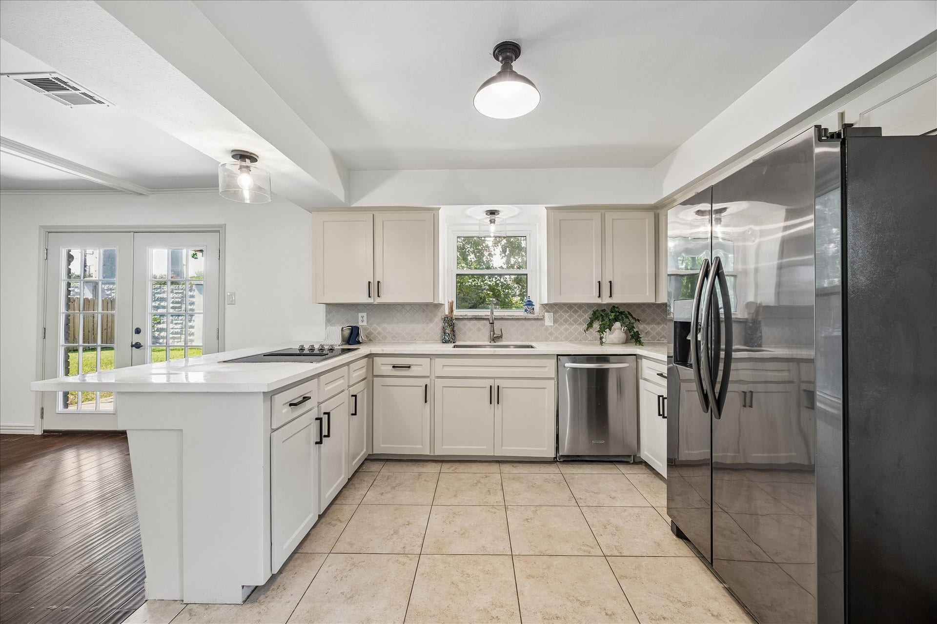 Spacious kitchen featuring white cabinetry, generous counter space, stainless steel appliances, and a breakfast bar overlooking the living area.