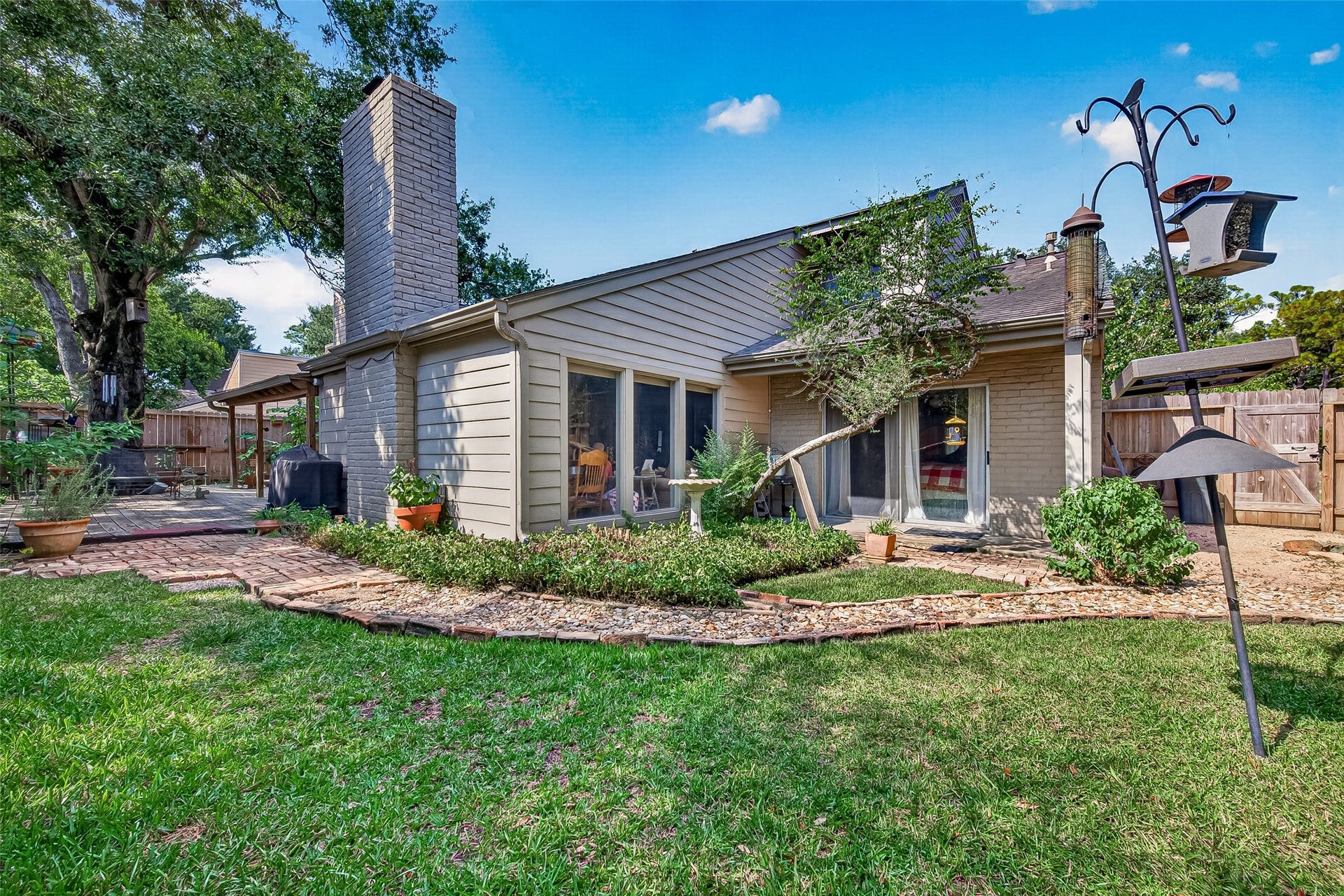 Backyard retreat with lush greenery, a cozy patio area, and ample space for outdoor relaxation, perfect for entertaining and enjoying nature.