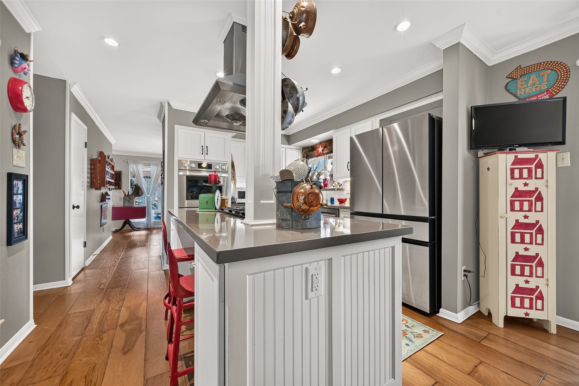 Kitchen with modern stainless steel appliances, sleek countertops, and warm wood floors. Cozy breakfast bar.