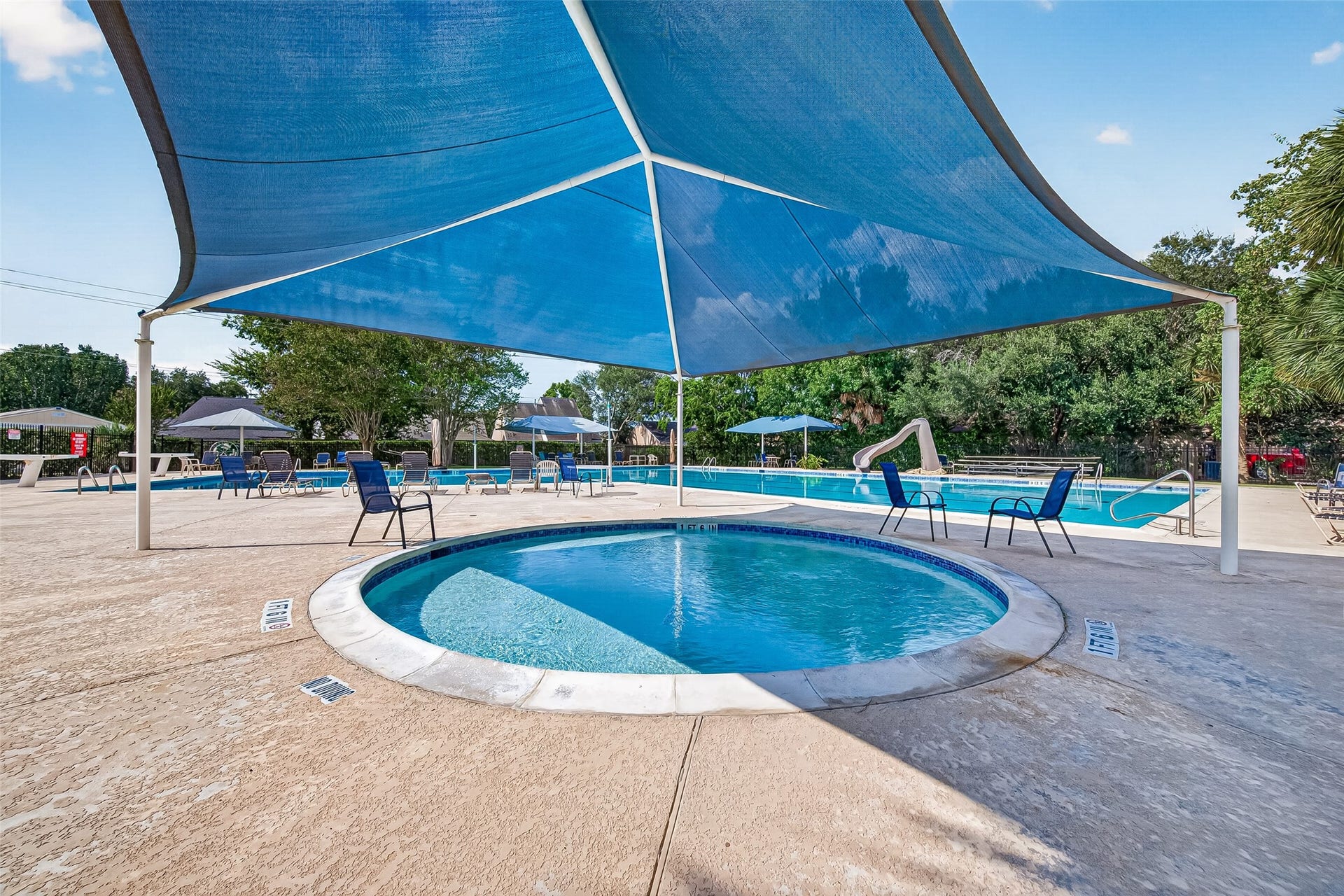 Relaxing oasis with a shaded pool area, featuring comfortable seating and lush greenery, perfect for unwinding and entertaining.