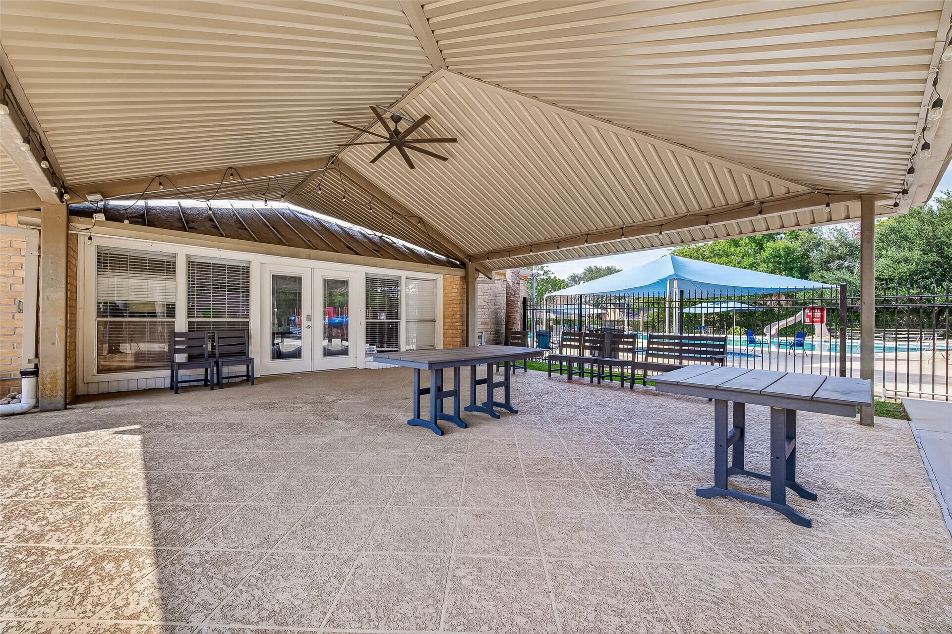 Utilize the neighborhood outdoor area in this spacious patio area, featuring a stylish pergola with ceiling fans, perfect for entertaining by the pool.