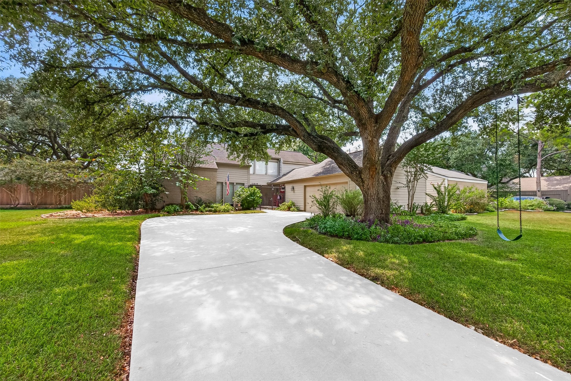 Charming home with a spacious two-car garage and a welcoming front yard framed by mature trees and lush greenery.