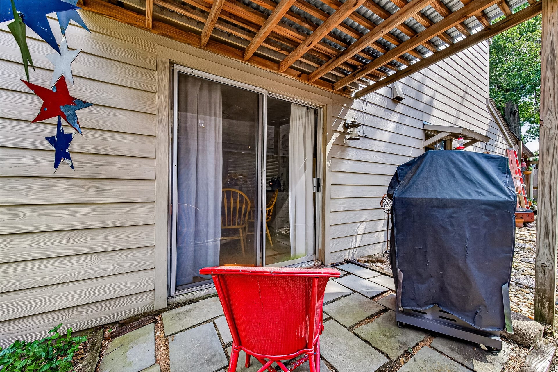 Patio area with stone pavers, perfect for outdoor relaxation, featuring a covered grill space and sliding glass doors leading inside. Ideal for entertaining and enjoying the fresh air.
