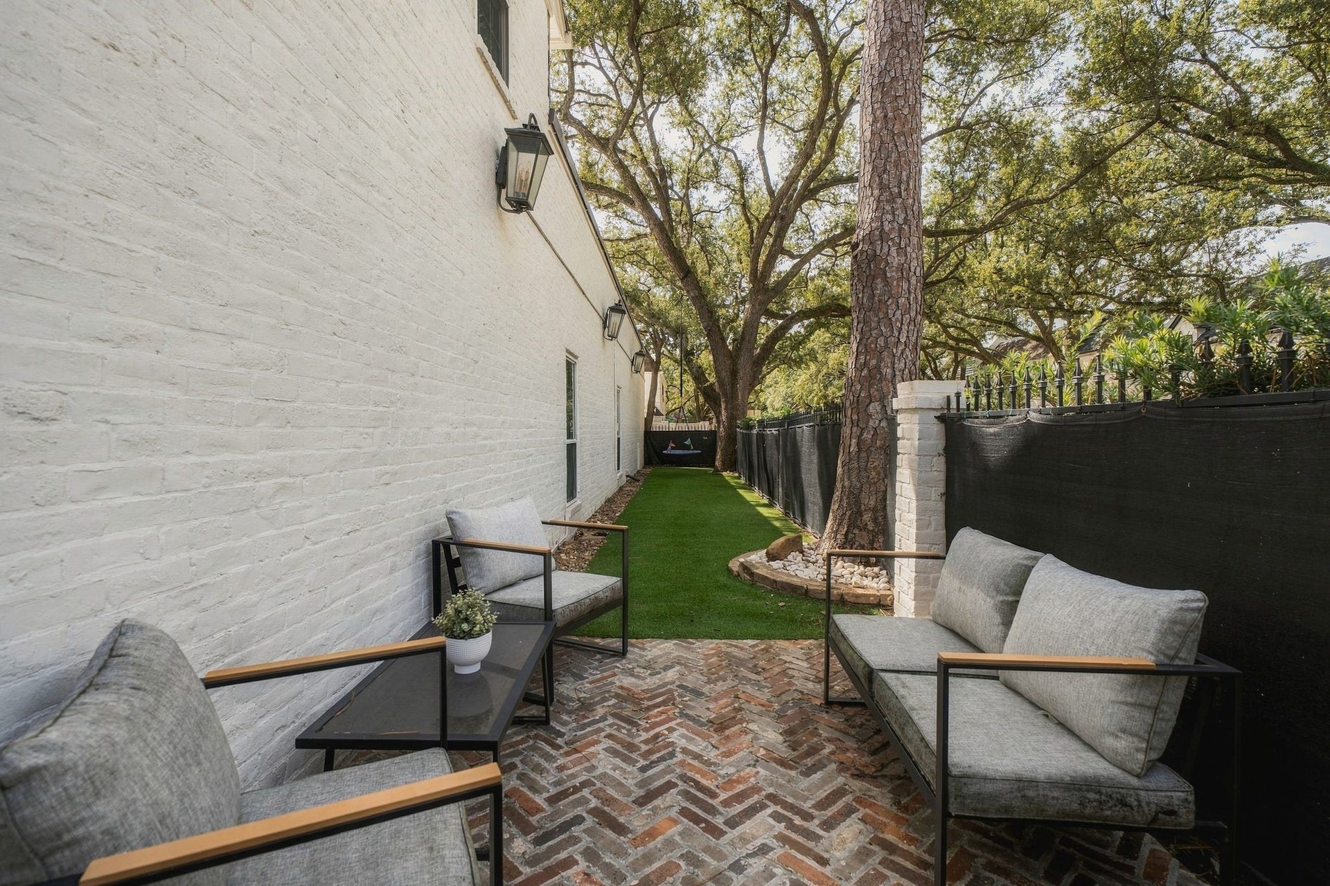 8619 La Fonte Street, Houston, TX 77024 The private turfed side yard begins with a brick-paved seating area, creating a comfortable spot for outdoor furniture just beyond the home. Mature trees provide shade overhead, while the fully fenced setting offers added privacy.