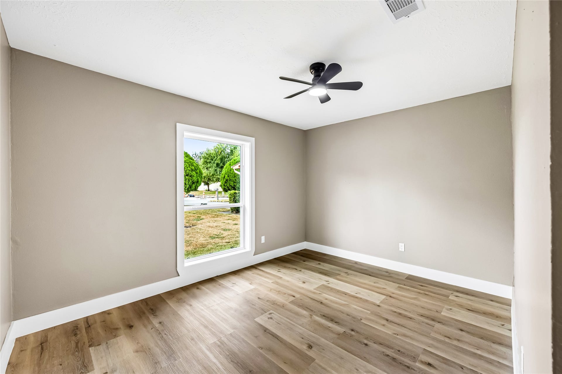 1803 Thornbrook Drive, Missouri City, TX 77489 Bright and comfortable bedroom featuring warm wood-look flooring, neutral walls, crisp white trim, and a modern ceiling fan