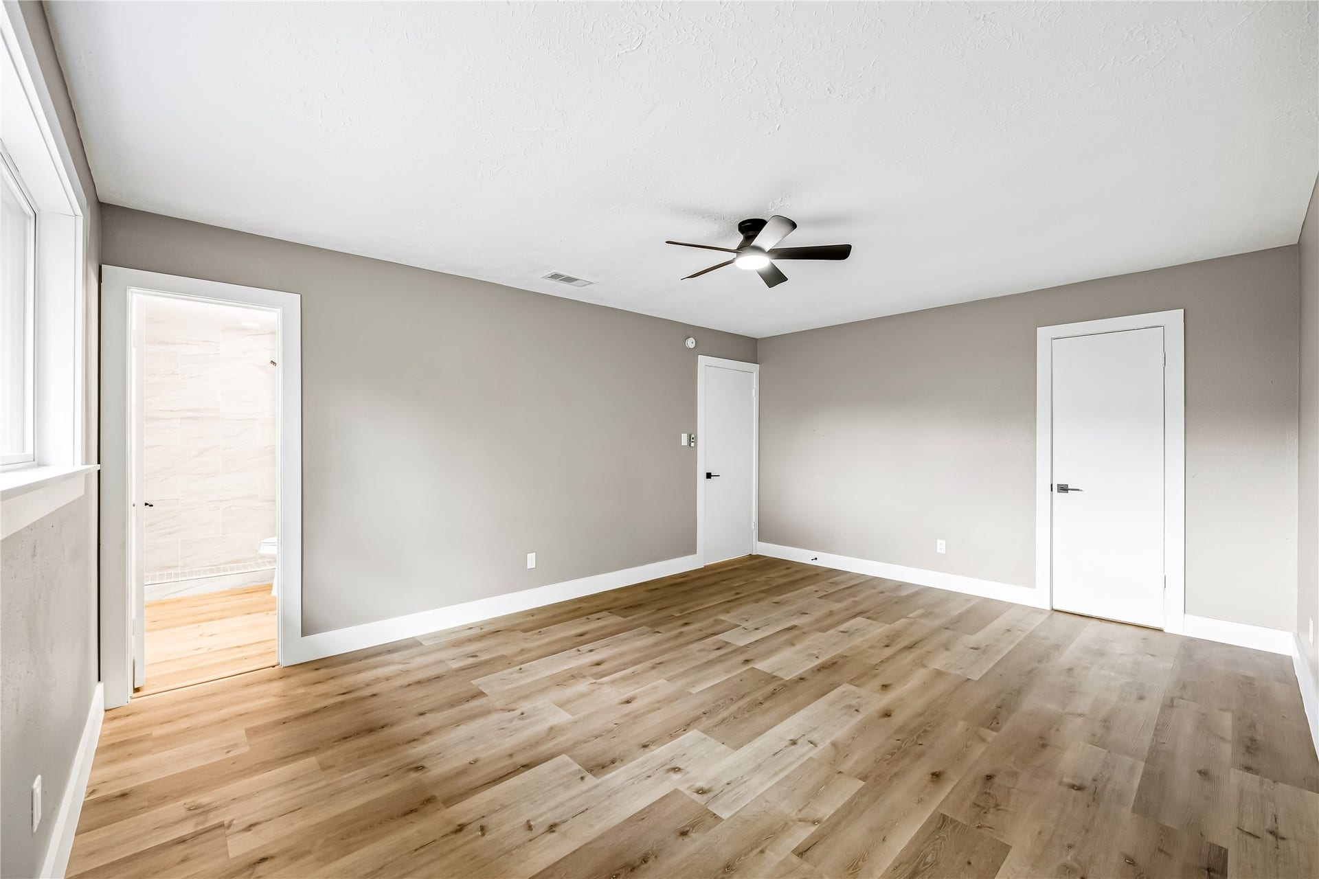 1803 Thornbrook Drive, Missouri City, TX 77489 Spacious bedroom featuring warm wood-look flooring, neutral walls, a modern ceiling fan, and plenty of natural light.