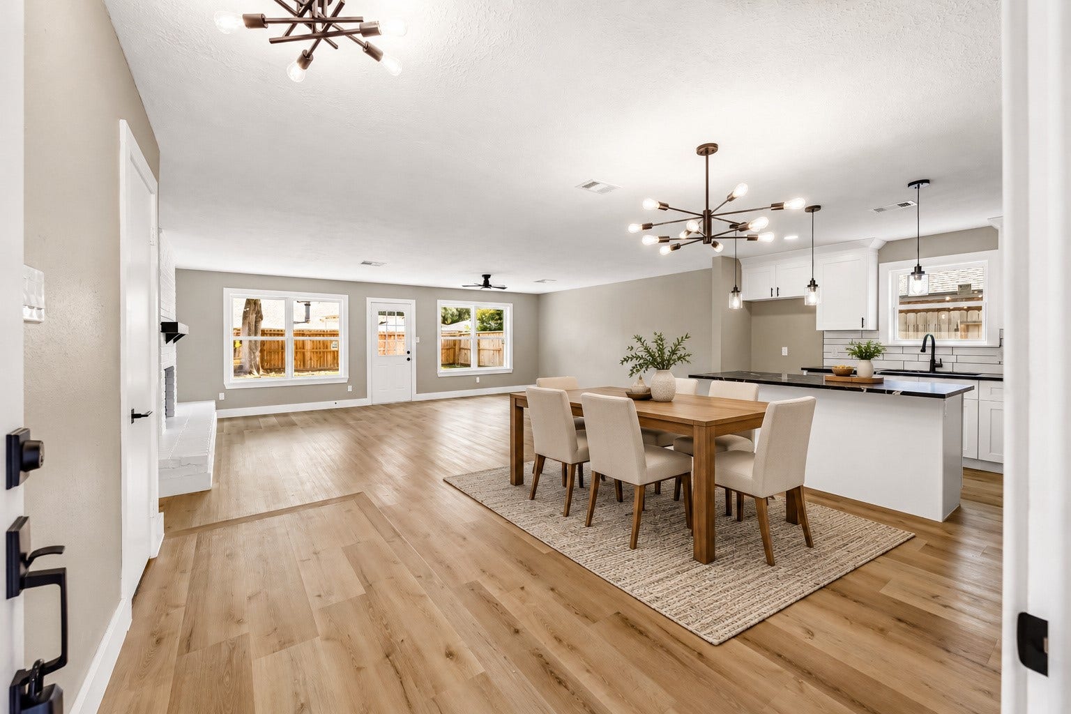 1803 Thornbrook Drive, Missouri City, TX 77489 Beautiful open-concept living, dining, and kitchen area featuring warm wood-look flooring, modern statement lighting, a large center island, white cabinetry, and sleek black accents. The spacious layout and abundance of natural light create a bright, stylish setting perfect for everyday living and entertaining.