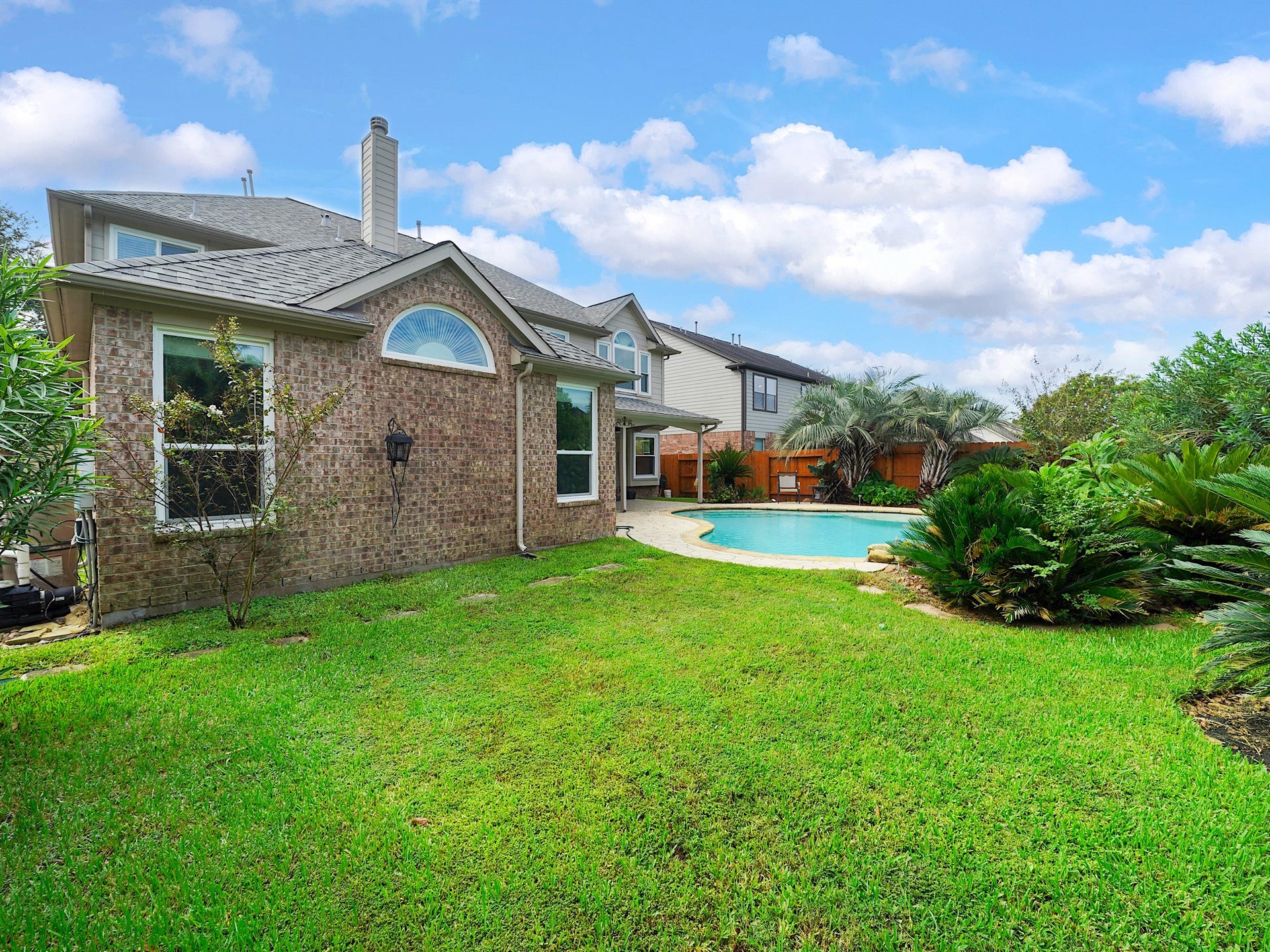 Beyond the pool, a wide lawn creates space for pets, play, gardening, or outdoor gatherings.