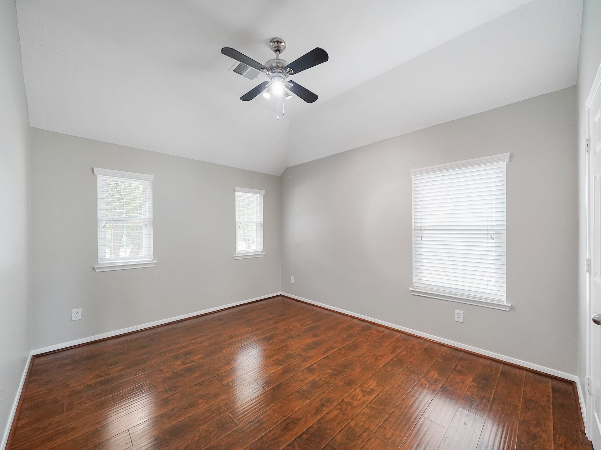 Wood floors, multiple windows, and a ceiling fan make this secondary room bright and adaptable.