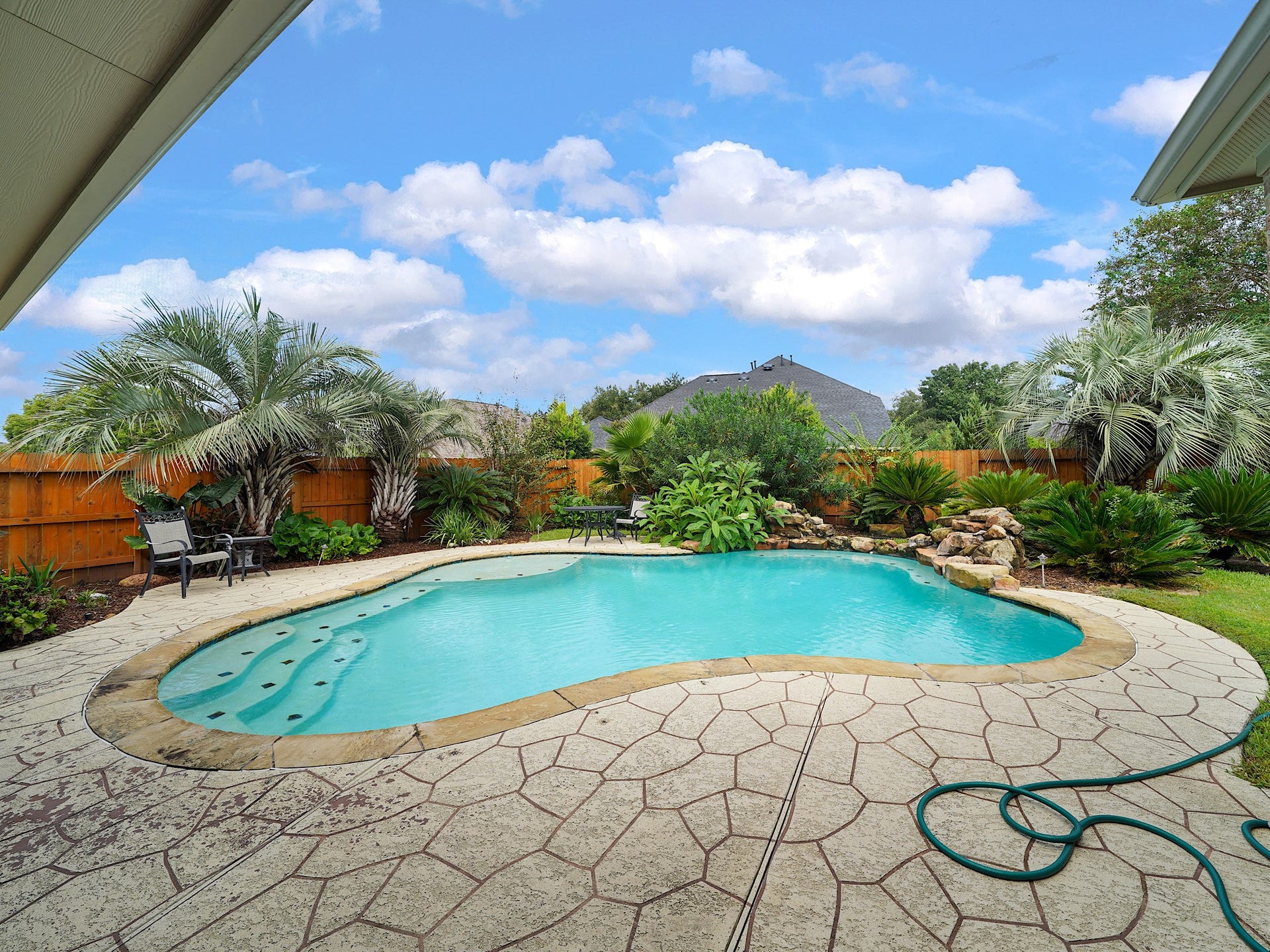 A sparkling pool becomes the centerpiece of the backyard, framed by a generous stone patio for lounging and entertaining.