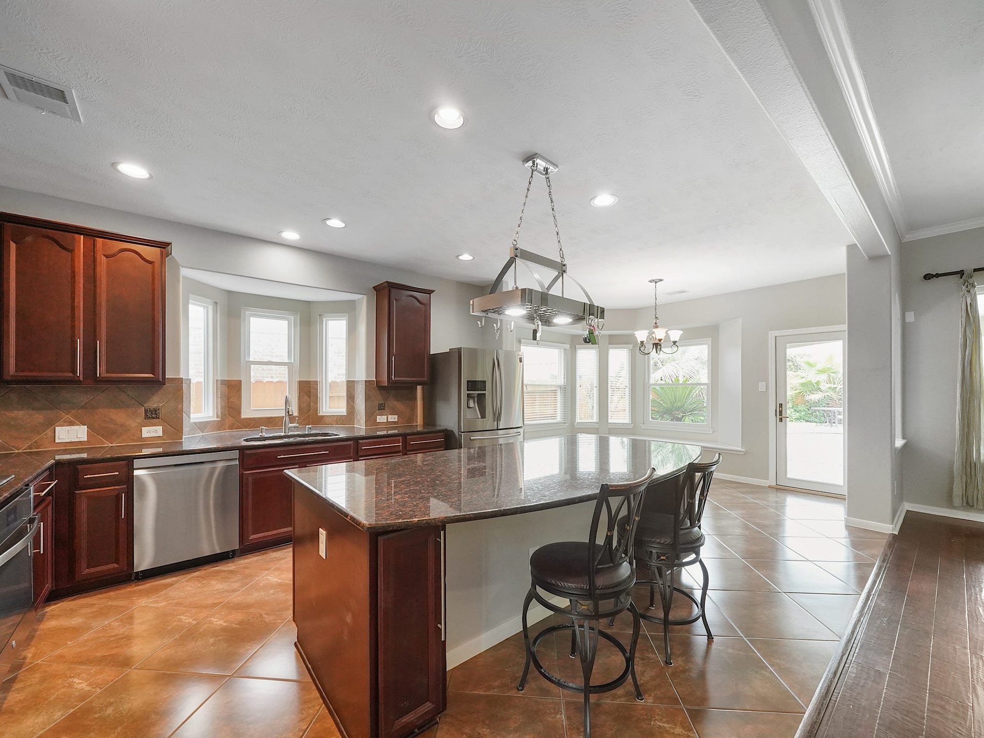 Another view highlights the kitchens ample storage, stainless steel appliances, and easy connection to the adjoining living areas.