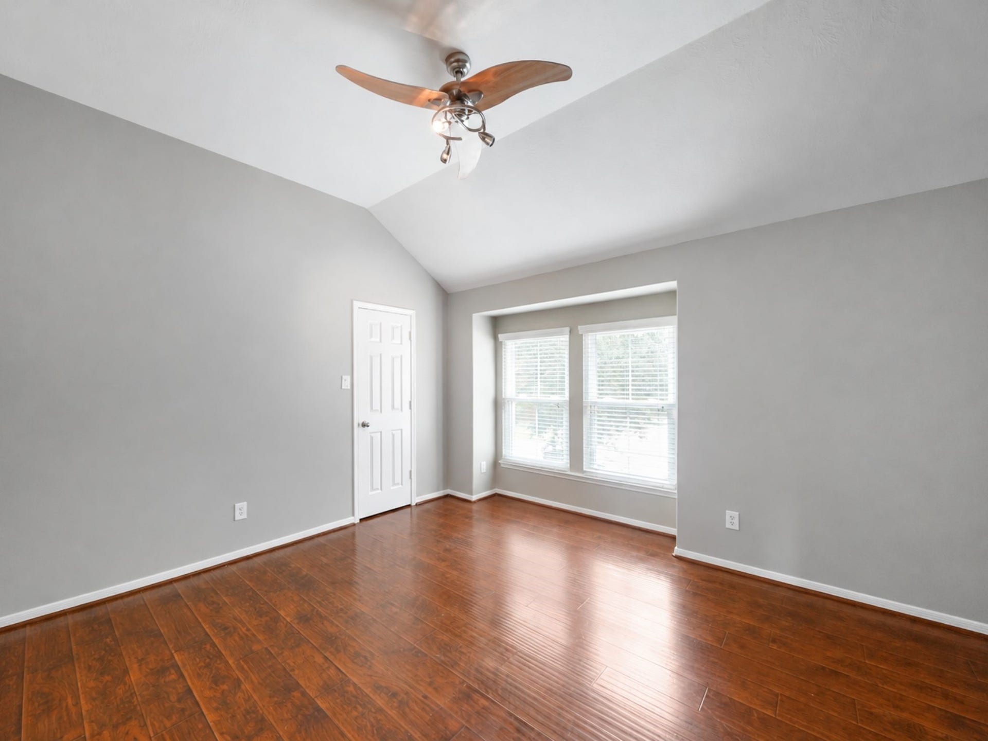 The generous secondary bedroom offers a flexible footprint, rich wood floors, and a charming window alcove.
