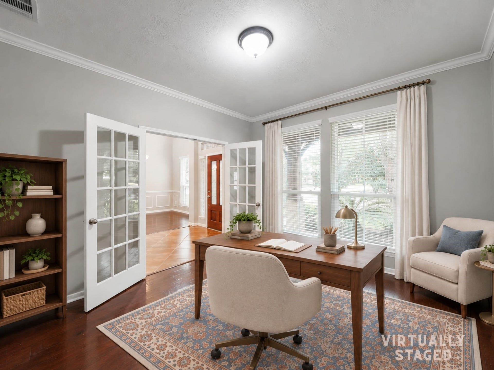 Virtually staged: French doors open to a light-filled study with rich wood floors and a polished setting for work, reading, or quiet focus.